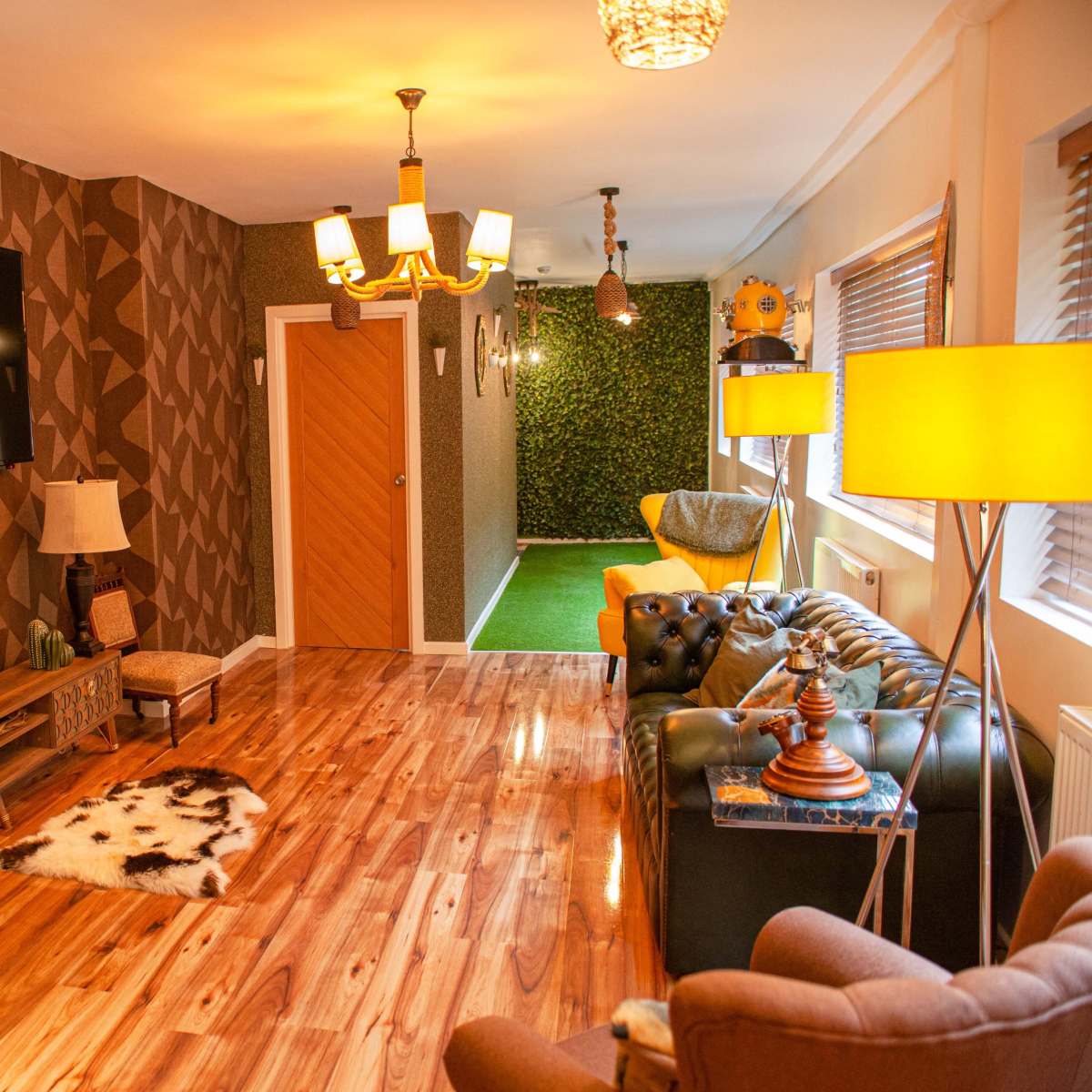 A modern living room featuring wooden flooring, a large TV mounted on a patterned wall, and various decorative elements like lamps and a cowhide rug.