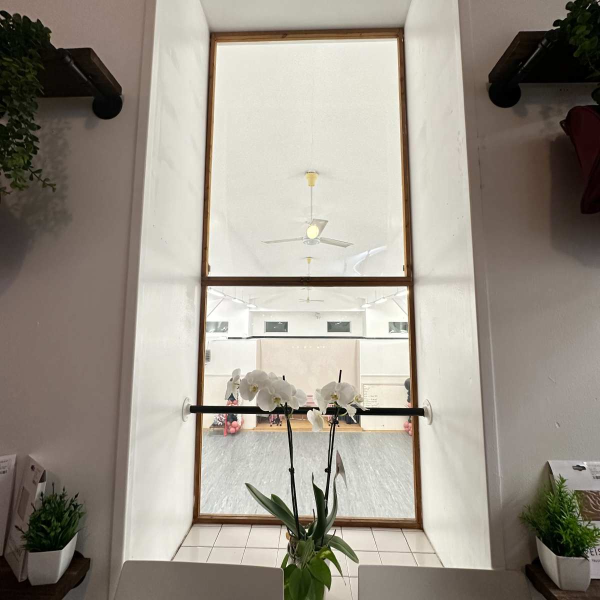 A large rectangular window framed in wood, overlooking a space with people and a horse inside.