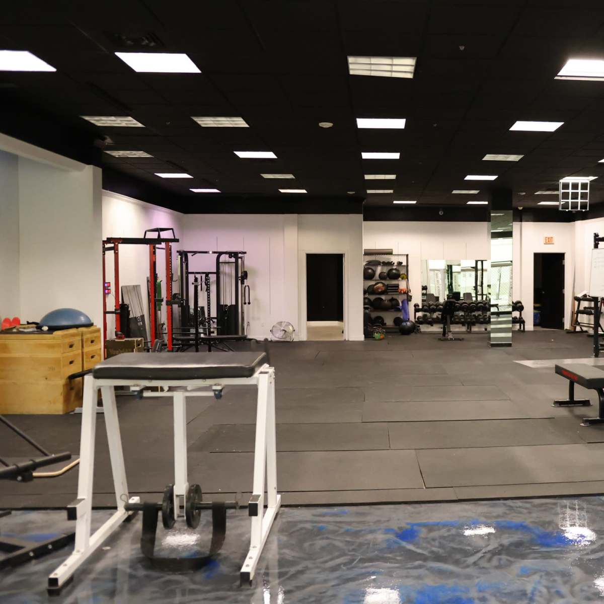 A spacious gym interior equipped with various weightlifting and fitness equipment, including benches and racks.