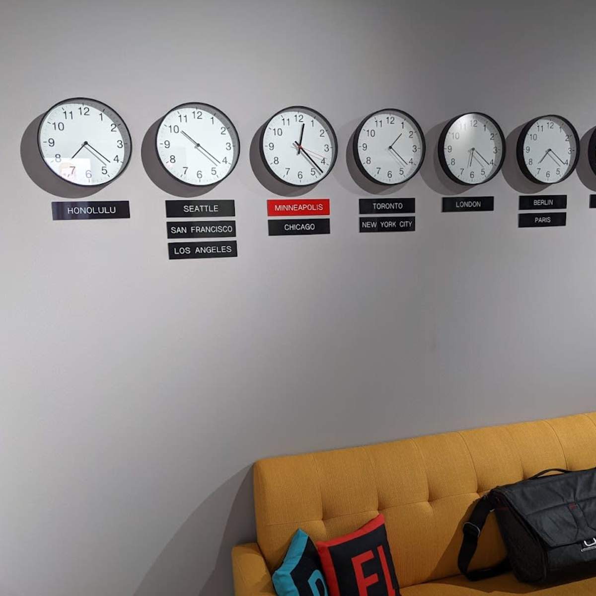 A wall displays eight clocks showing different times for various cities, accompanied by city labels beneath each clock.
