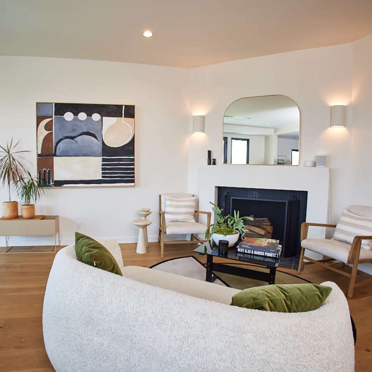 A modern living room features a cozy seating arrangement, a fireplace, and a large abstract painting on the wall.
