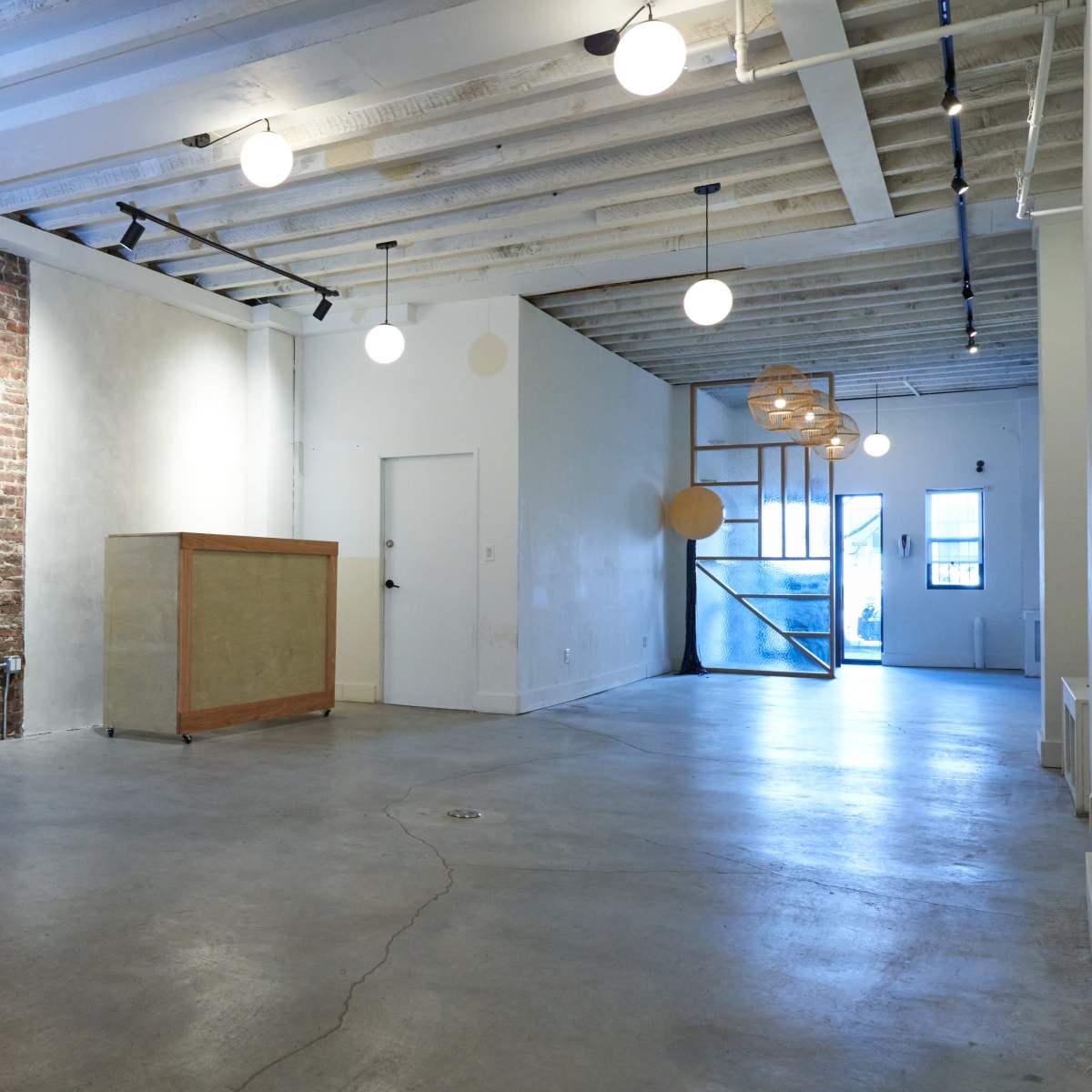 A spacious interior with exposed brick walls, concrete flooring, and modern light fixtures.
