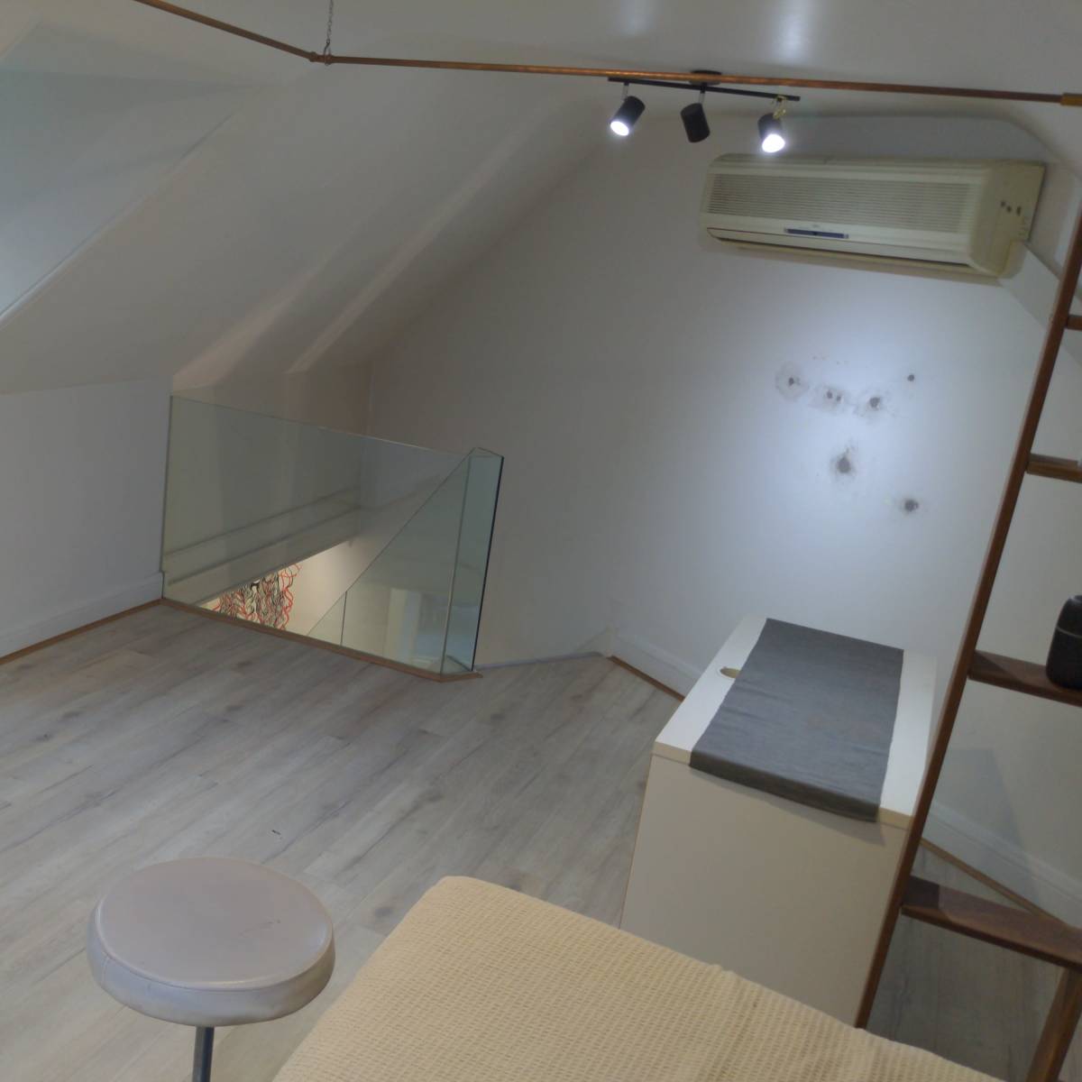An attic room with sloped ceilings, a small stool, a mirror on the floor, and minimal furniture.