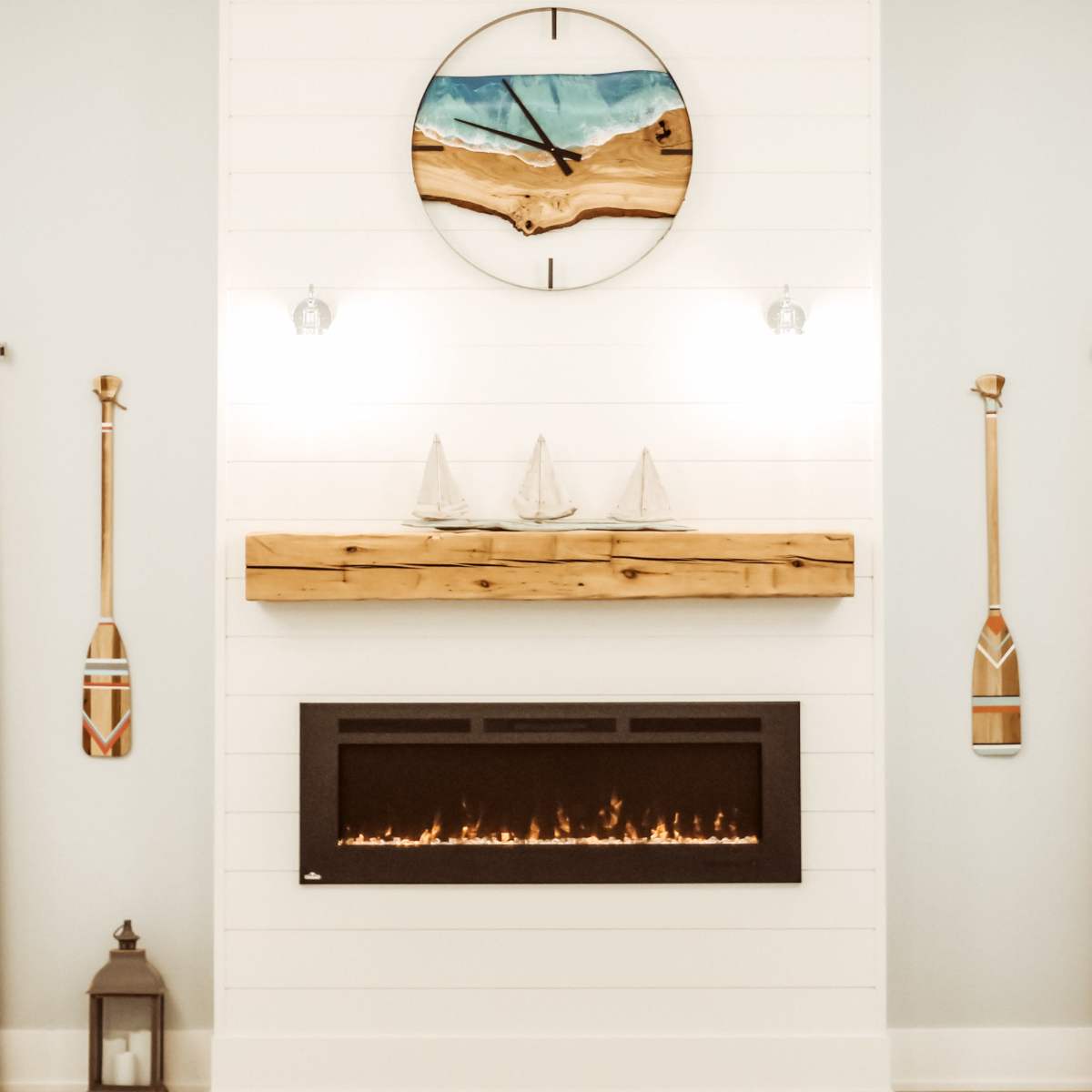 A modern fireplace beneath a circular wooden clock, flanked by decorative oars and illuminated by wall sconces.