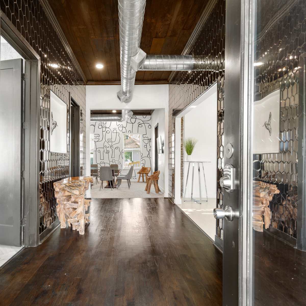 A hallway features hexagonal mirror tiles on the walls, leading to a spacious room with a modern design and wooden elements.