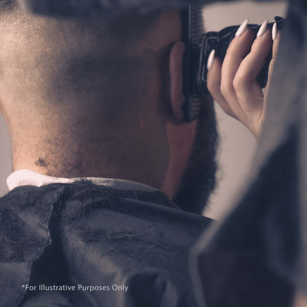 A person with a very short haircut receives a trim from a barber using an electric clipper.