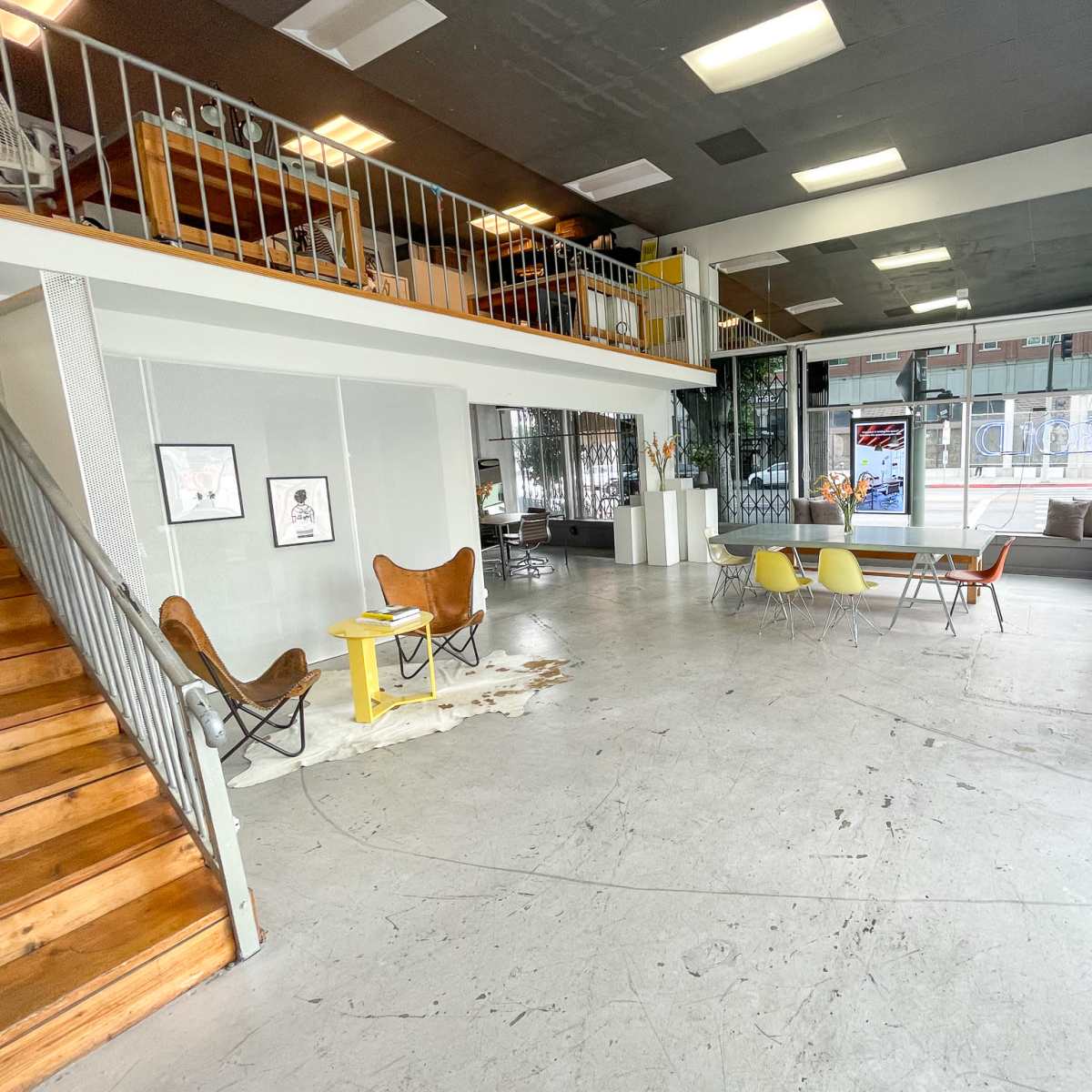 A spacious, modern interior with a staircase, seating areas, and large windows, allowing natural light to fill the space.