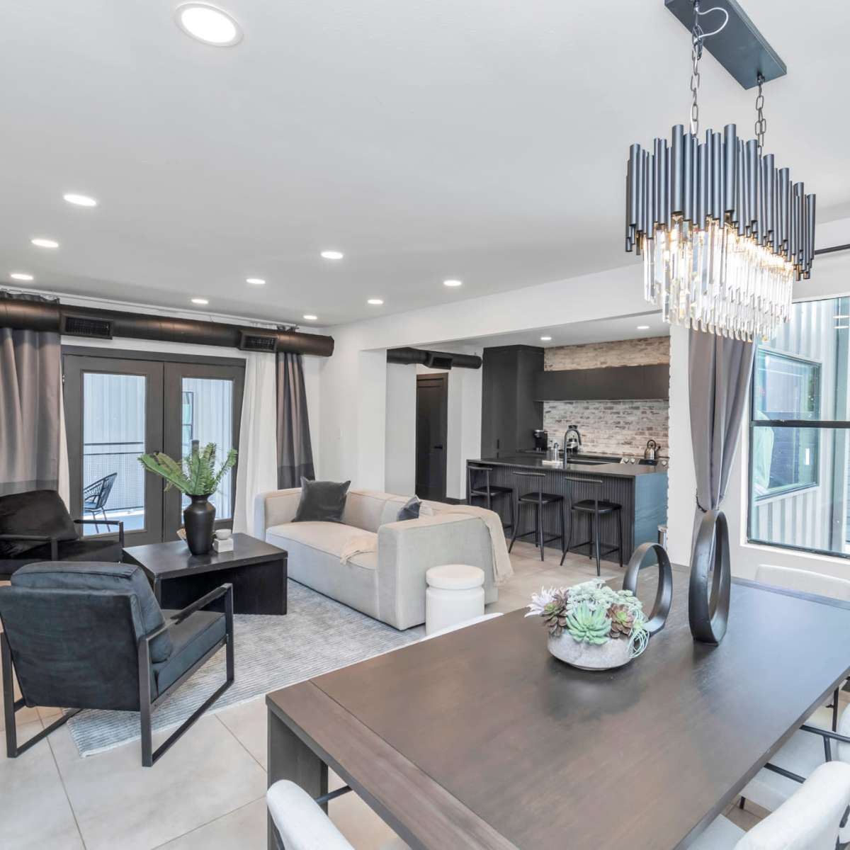 A modern living and dining area with a seating arrangement, a dining table, and large windows letting in natural light.