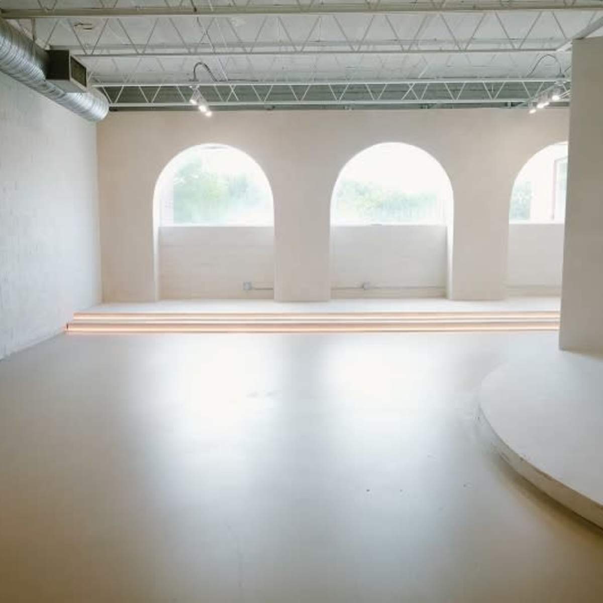 A spacious, airy interior with three large arched windows and a smooth, light-colored floor.