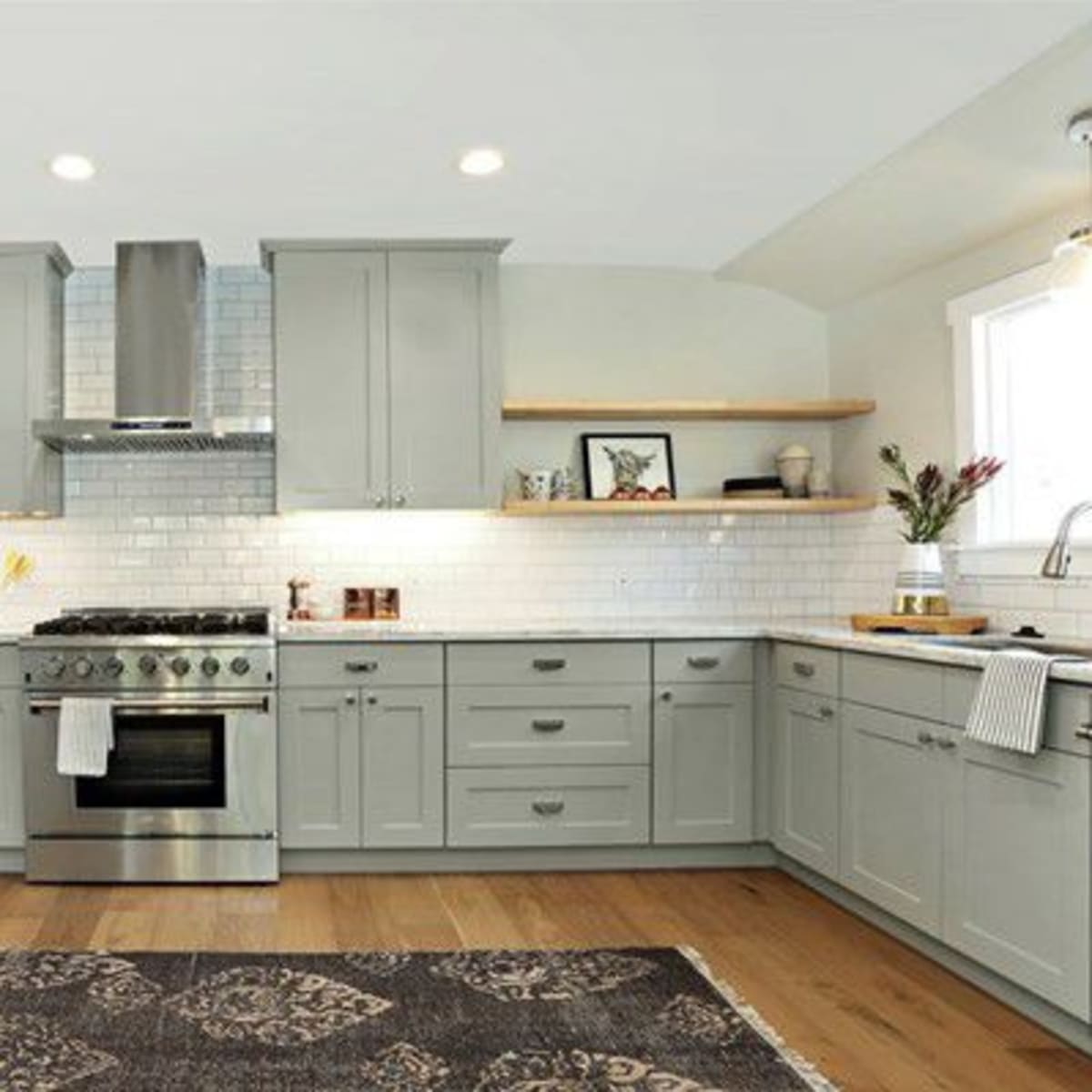 A modern kitchen with gray cabinets, stainless steel appliances, and a white tiled backsplash.