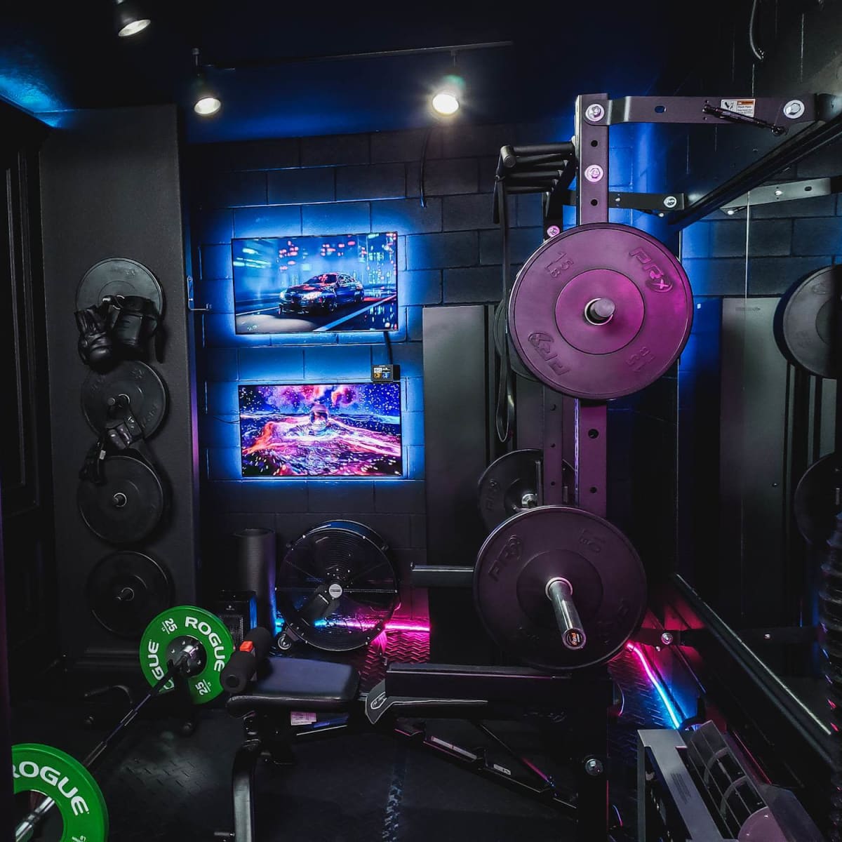 A gym space featuring a weightlifting setup, a punching bag, and a TV screen displaying vibrant visuals.