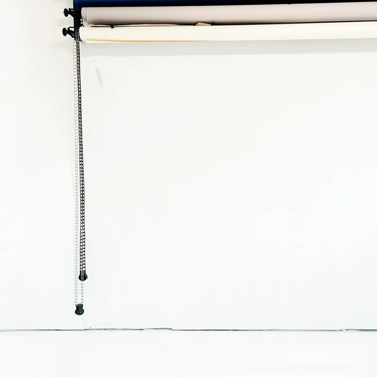 Several rolls of paper mounted on a wall, with a pull cord hanging down beside them.