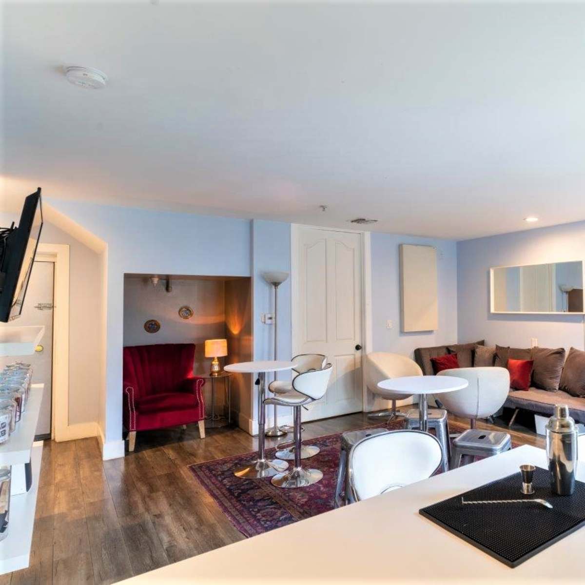 A modern lounge area featuring seating, tables, mirrors, and a decorative rug on the floor.
