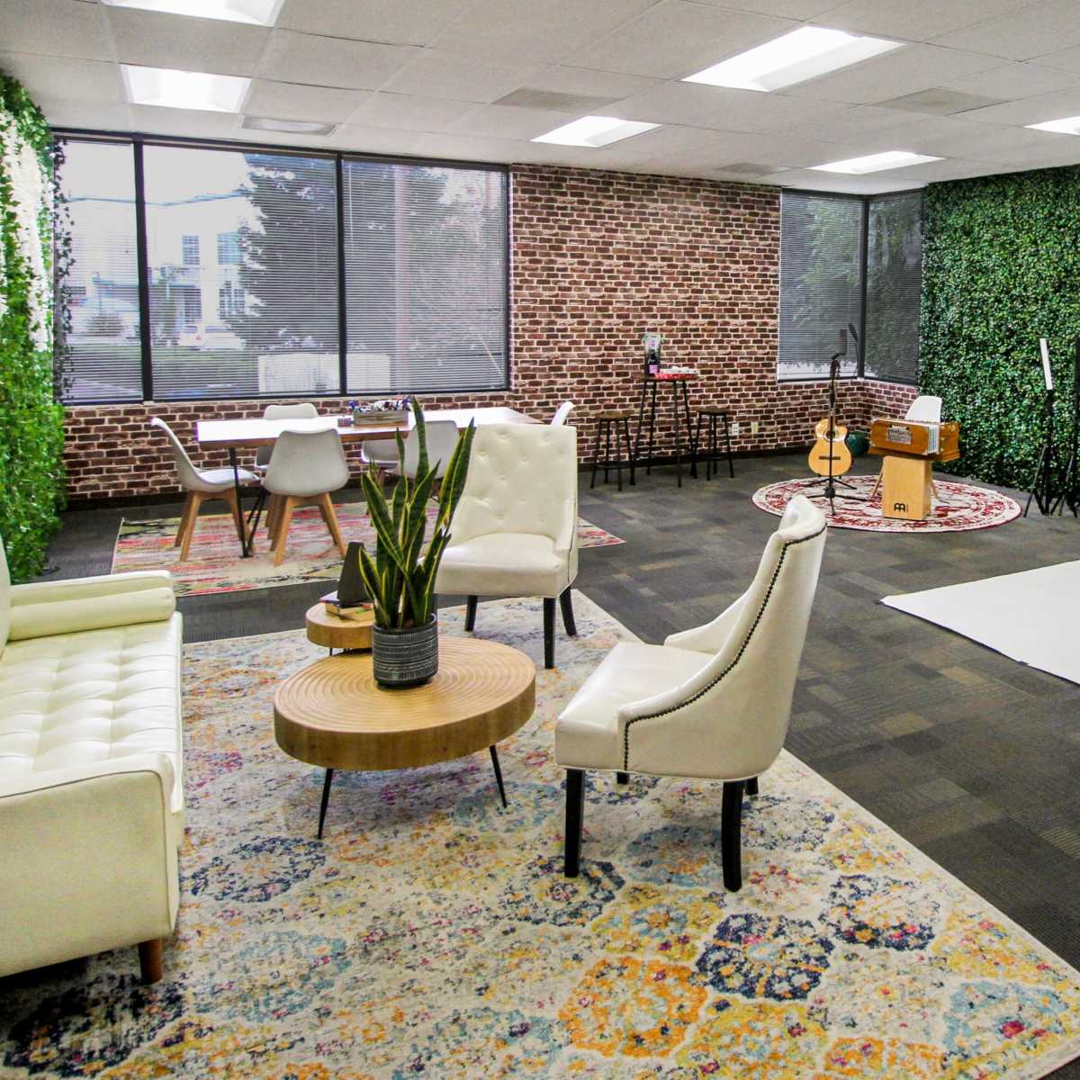 A modern studio with a seating area, a backdrop setup for photography, and green decorative elements on the walls.