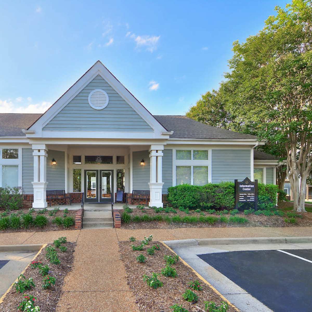 A light blue building with a triangular roof, large front windows, and landscaped greenery surrounding the entrance.
