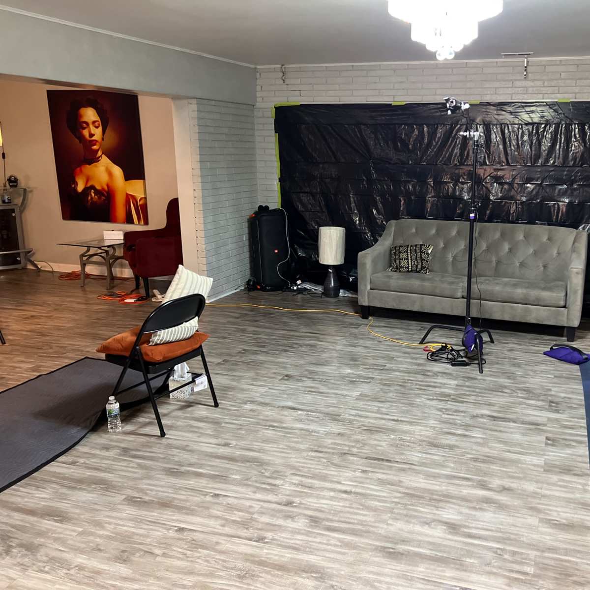 A spacious room with a gray couch, a black backdrop, and a setup for photography equipment.