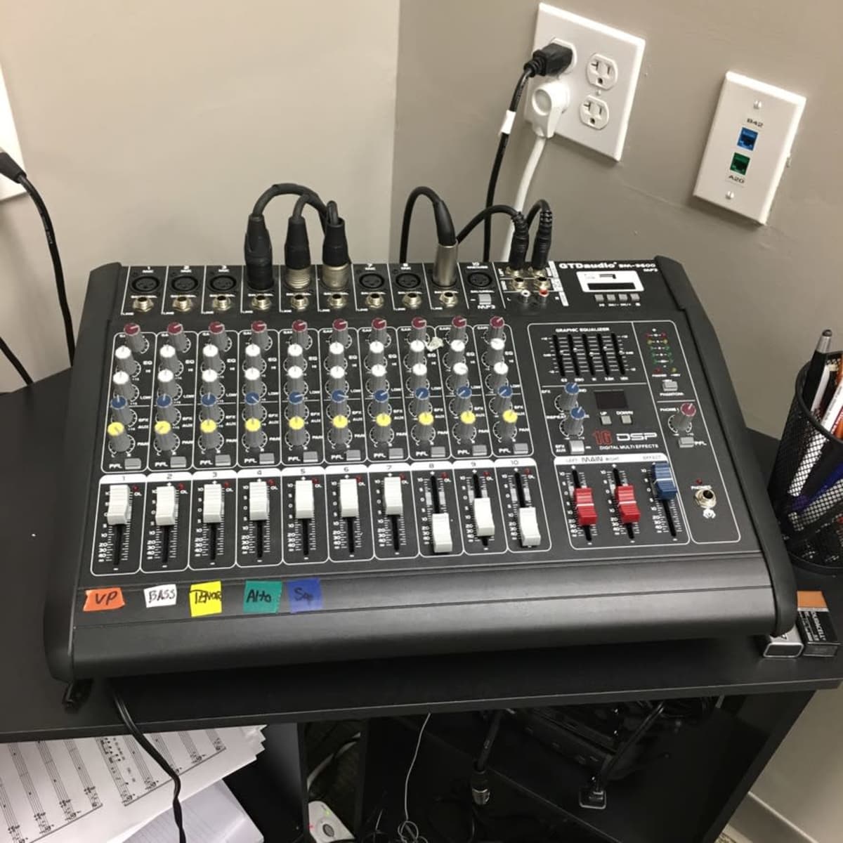 A multi-channel audio mixer with various knobs, faders, and connection ports on a desktop.