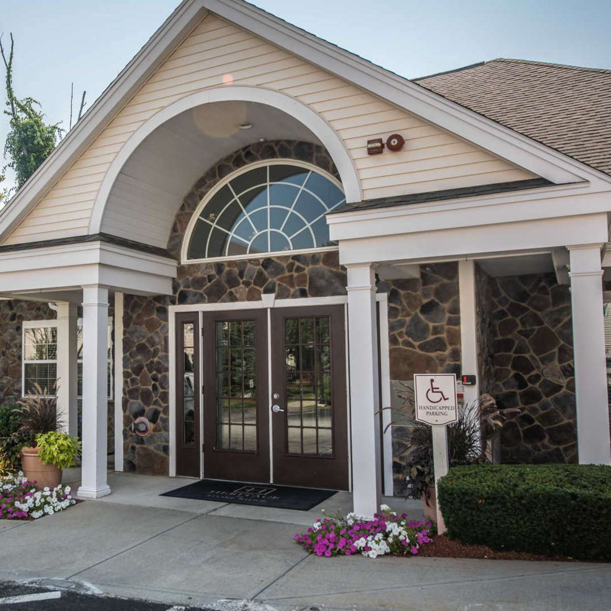 A leasing center clubhouse with a stone facade, large arched windows, and a landscaped entrance.