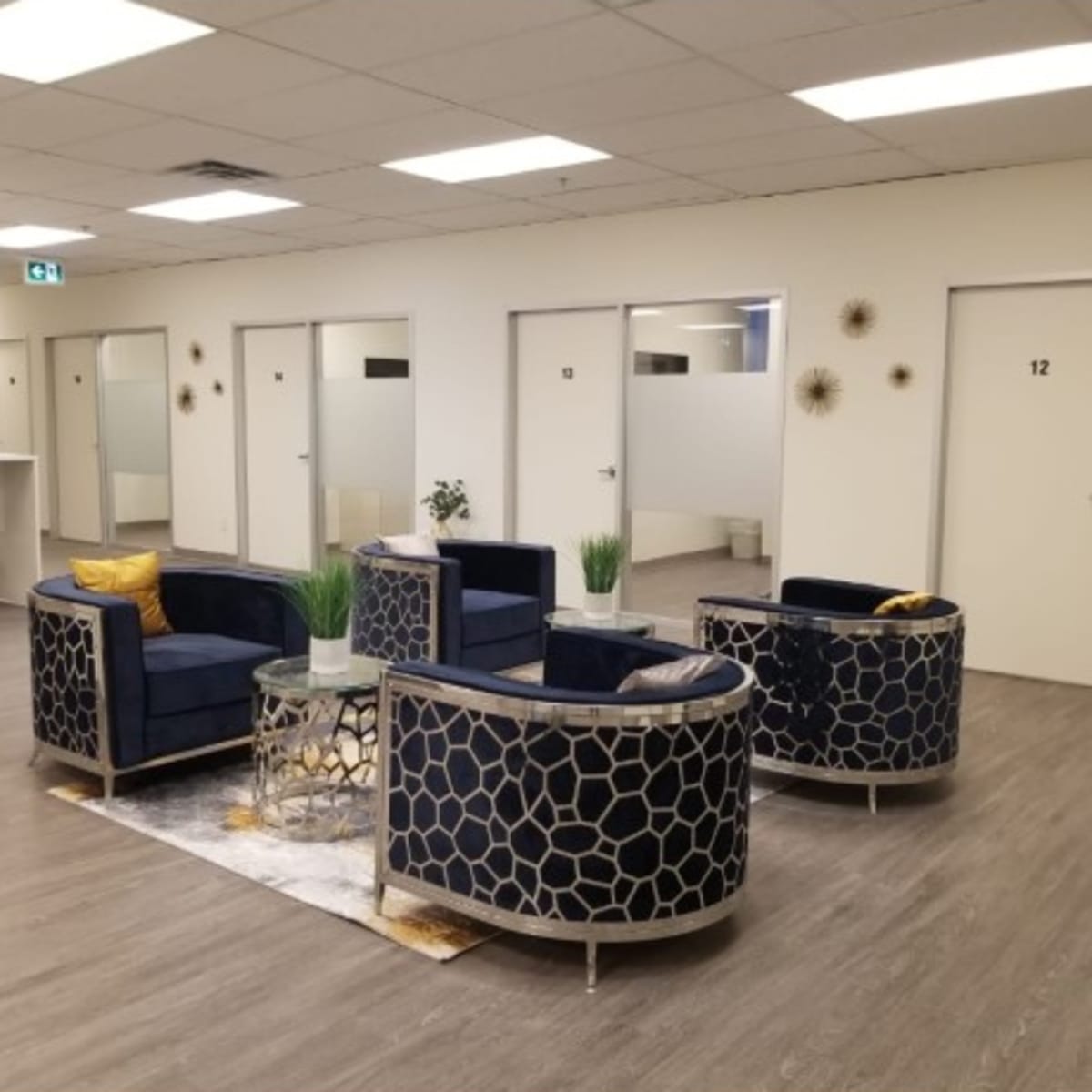 A waiting area with two circular sofas, a glass coffee table, and several closed office doors in a well-lit space.