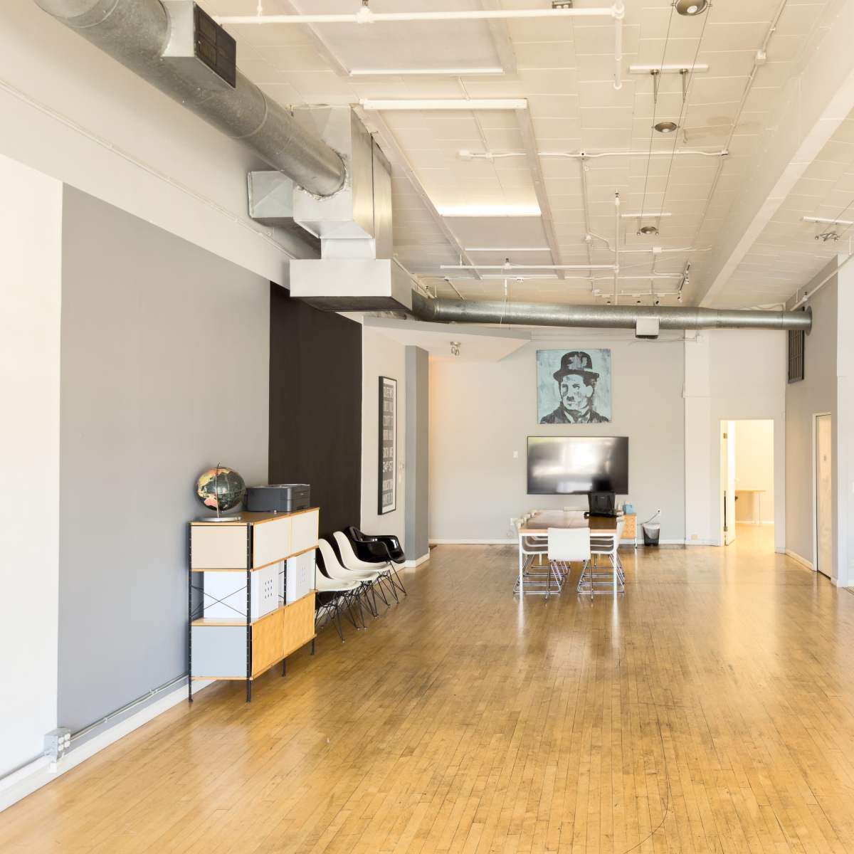 A spacious, modern interior with hardwood floors, minimalist furniture, and a large wall-mounted television.
