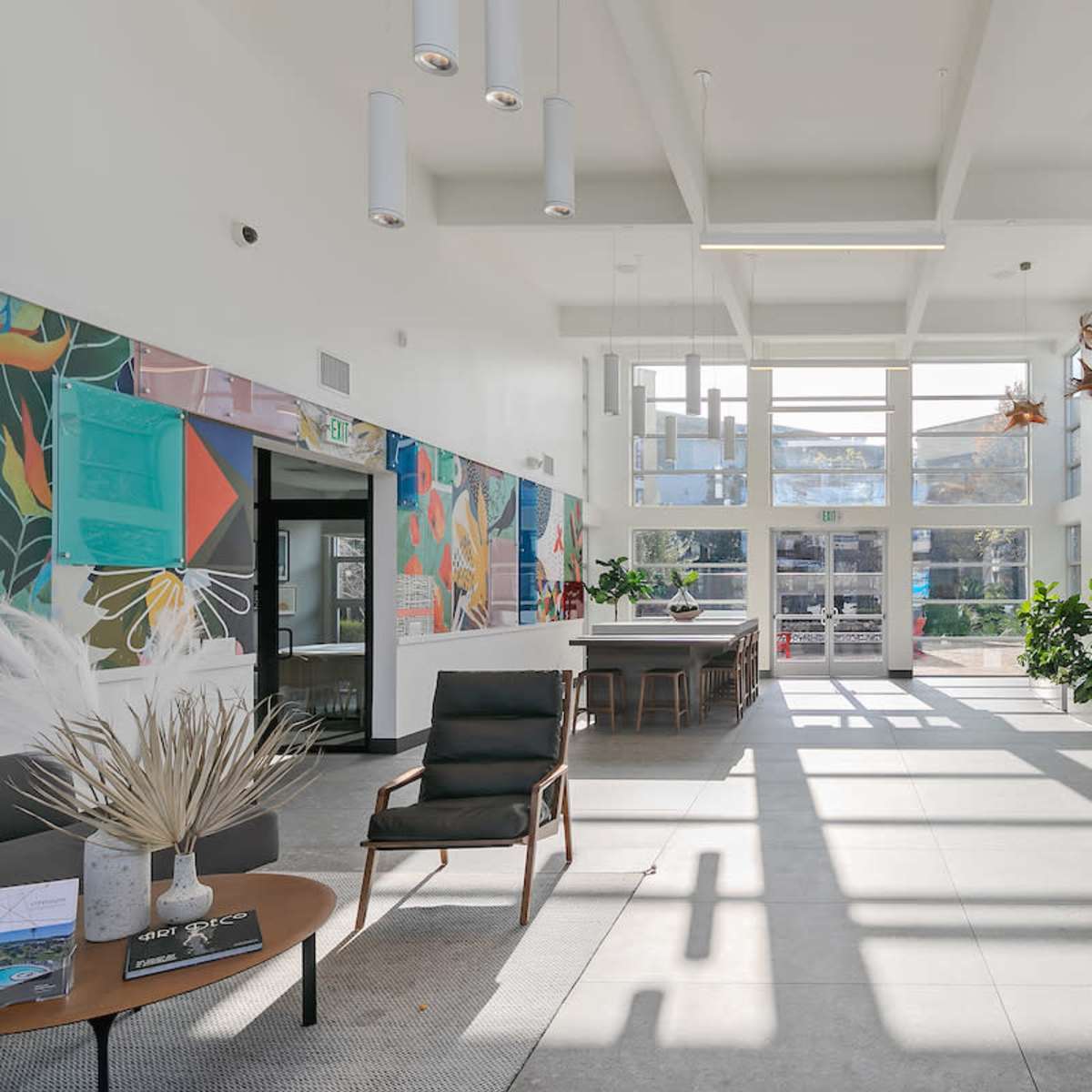 A bright lobby with large windows, modern furnishings, and potted plants.