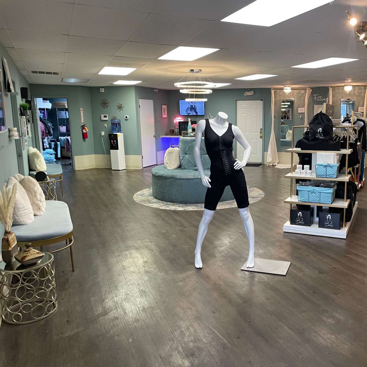 A fitness clothing boutique featuring a central display area with a mannequin wearing athletic apparel, surrounded by racks of clothing and accessories.