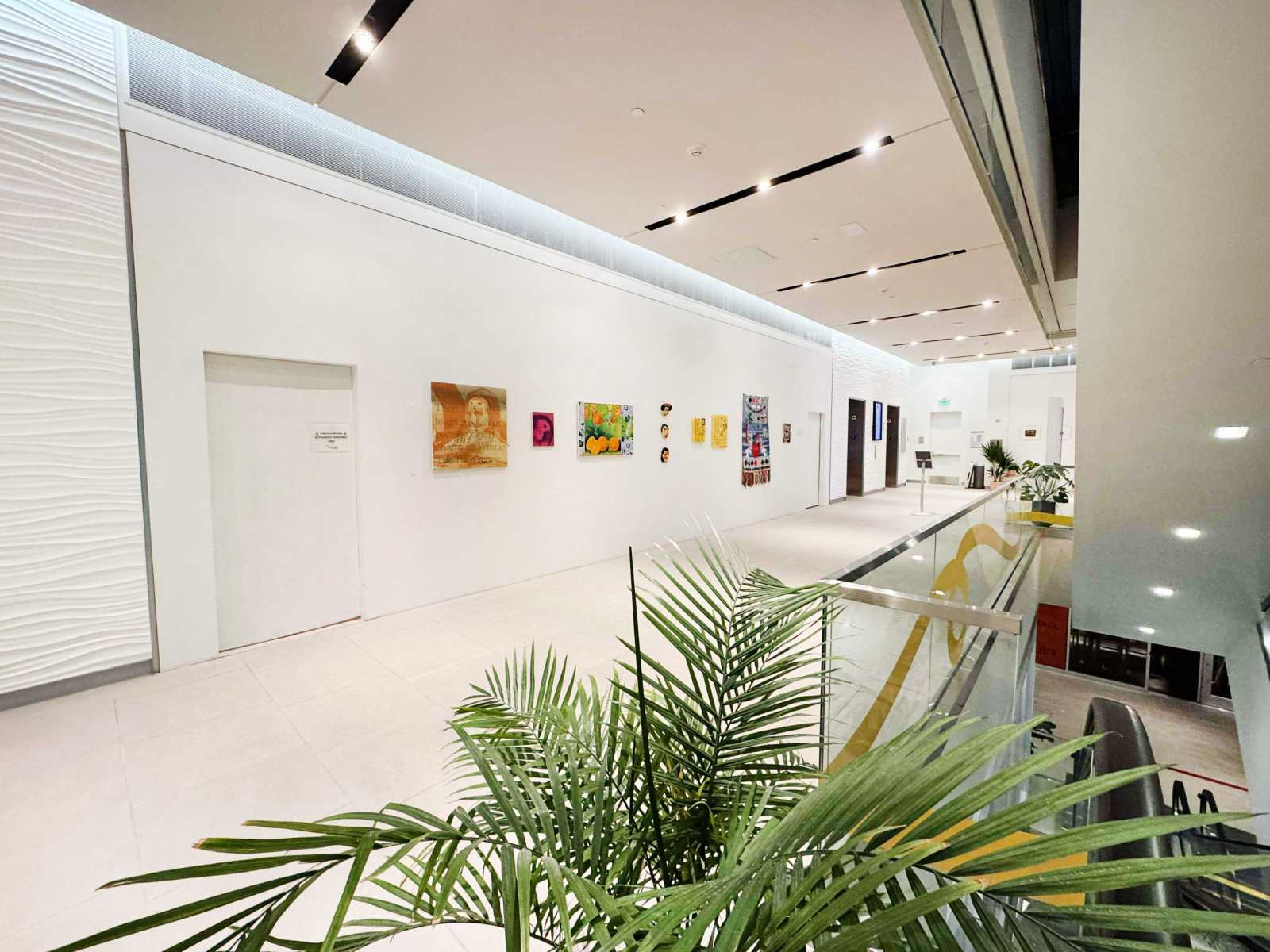 Open gallery interior with white walls, art, and glass railing