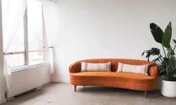 Light filled photo studio with orange accent couch