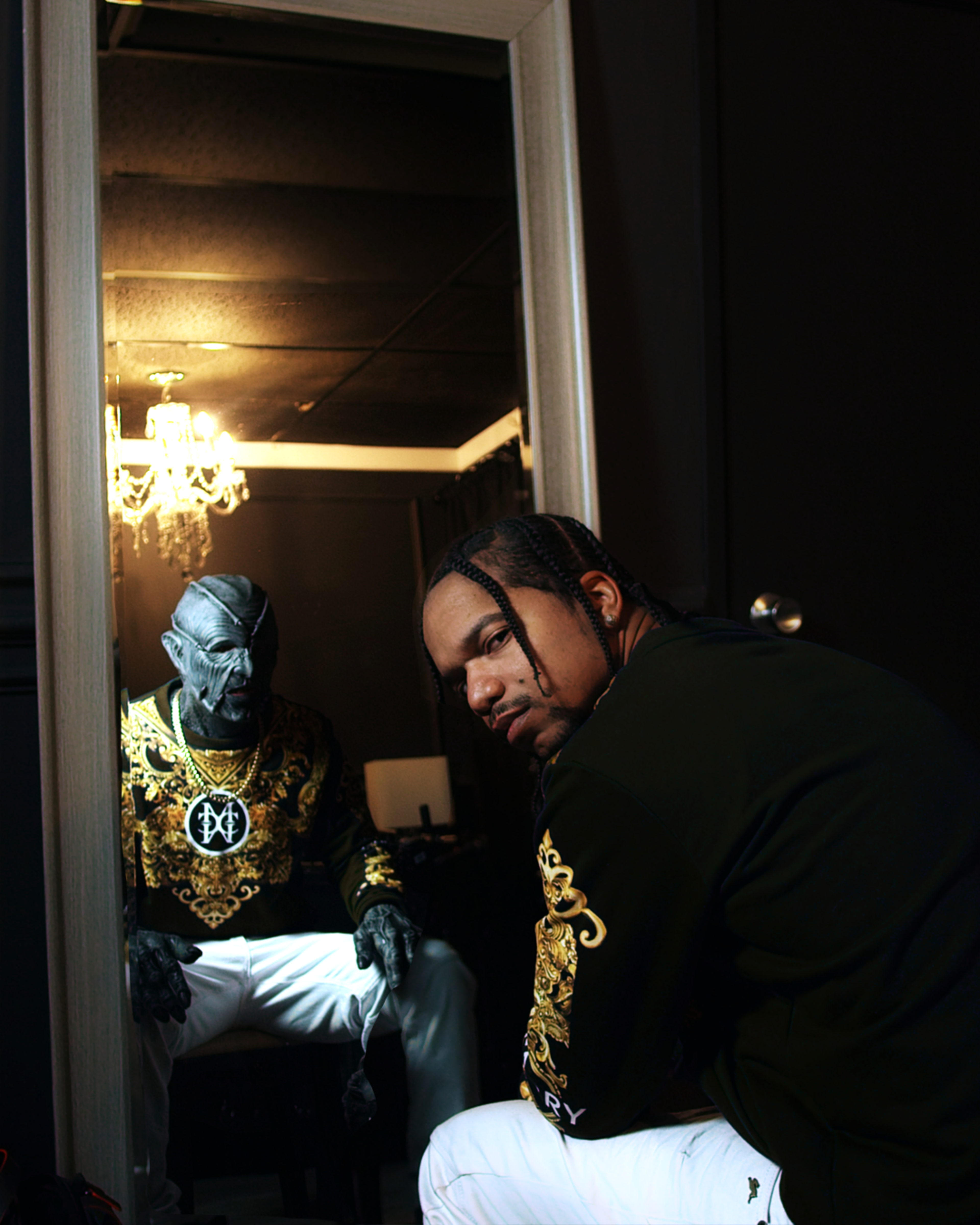 A man sits in front of a mirror with a reflection of a monster.