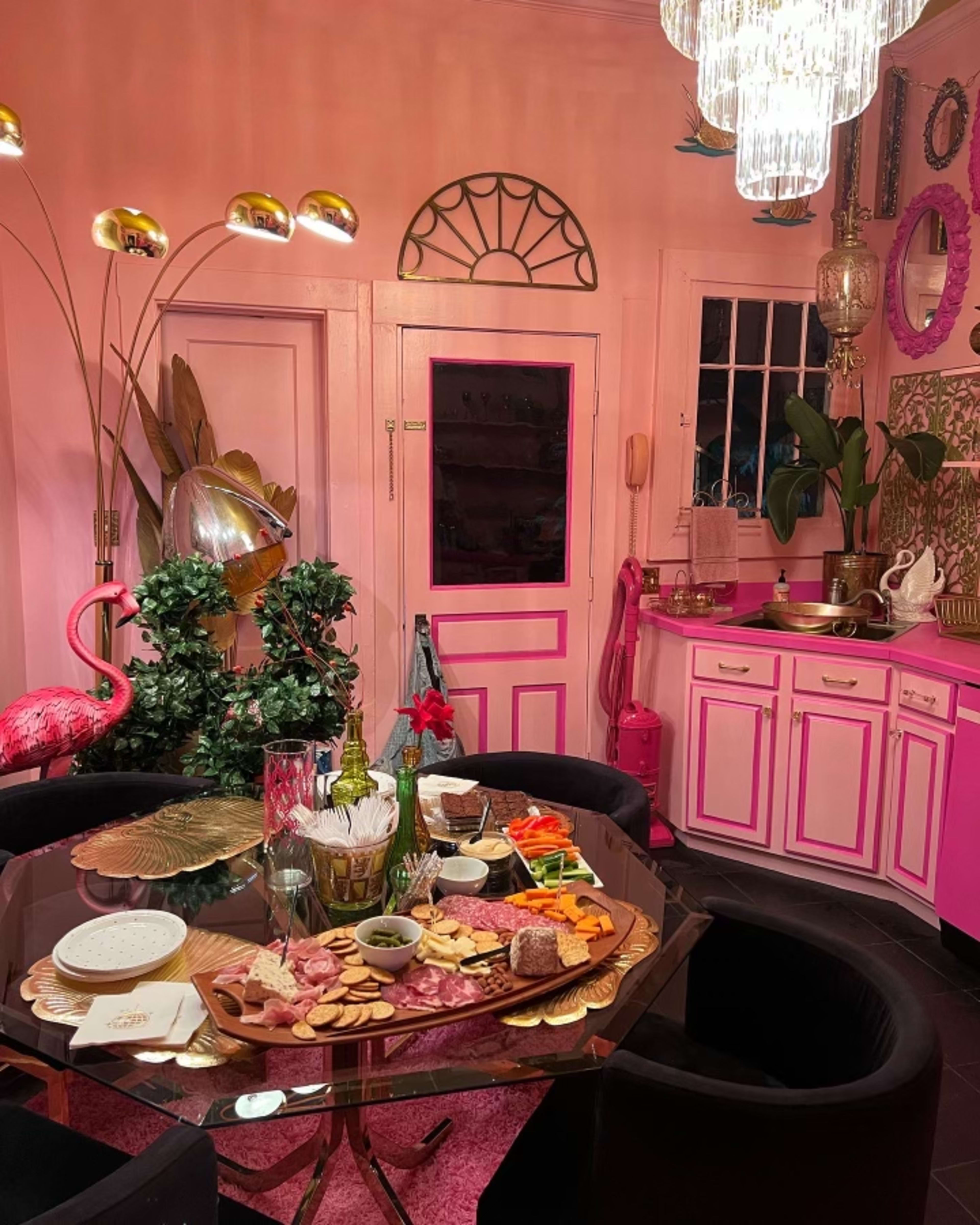 A retro dining room with pink walls and black chairs.