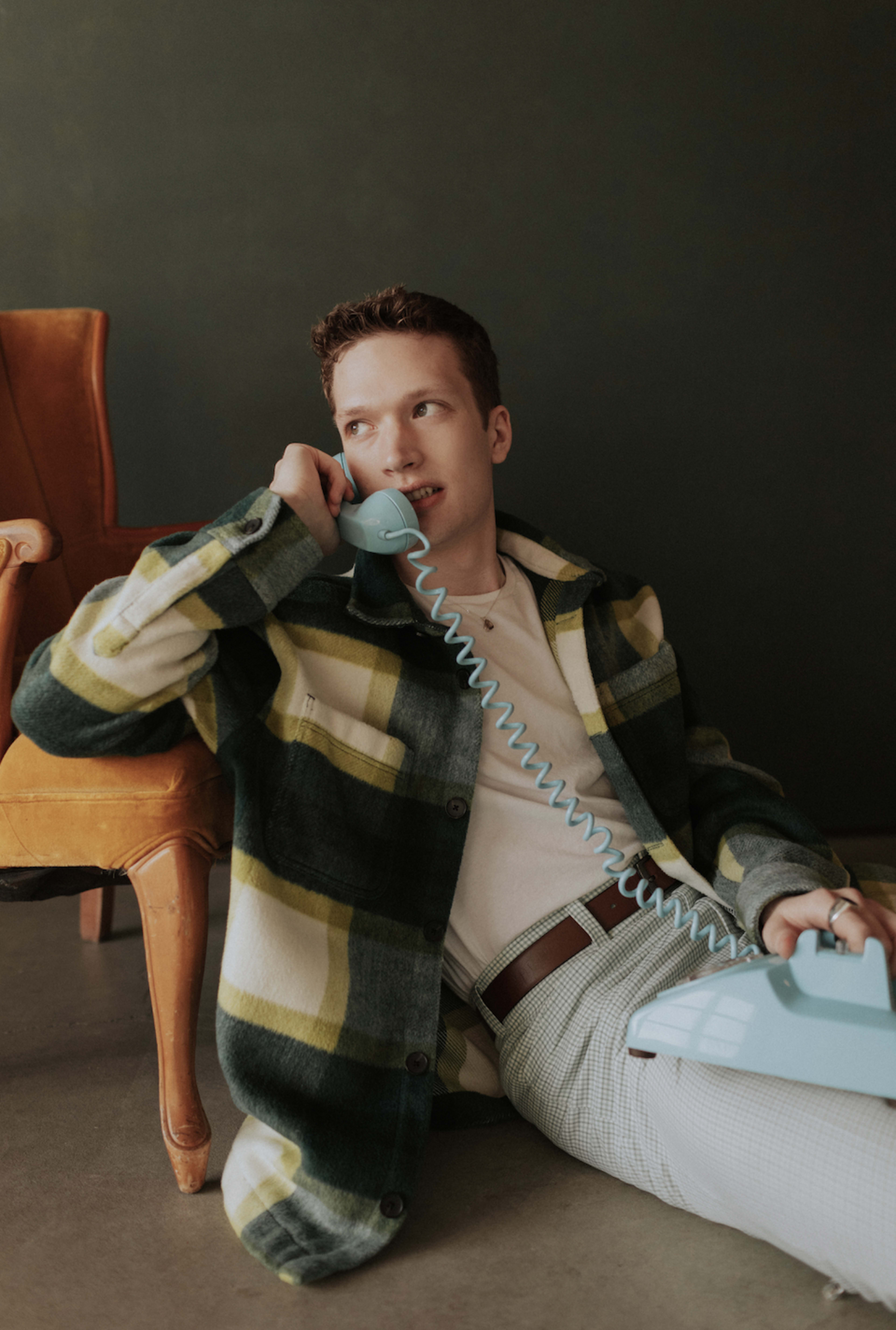 Un hombre posa con un teléfono para una sesión de fotos retro.