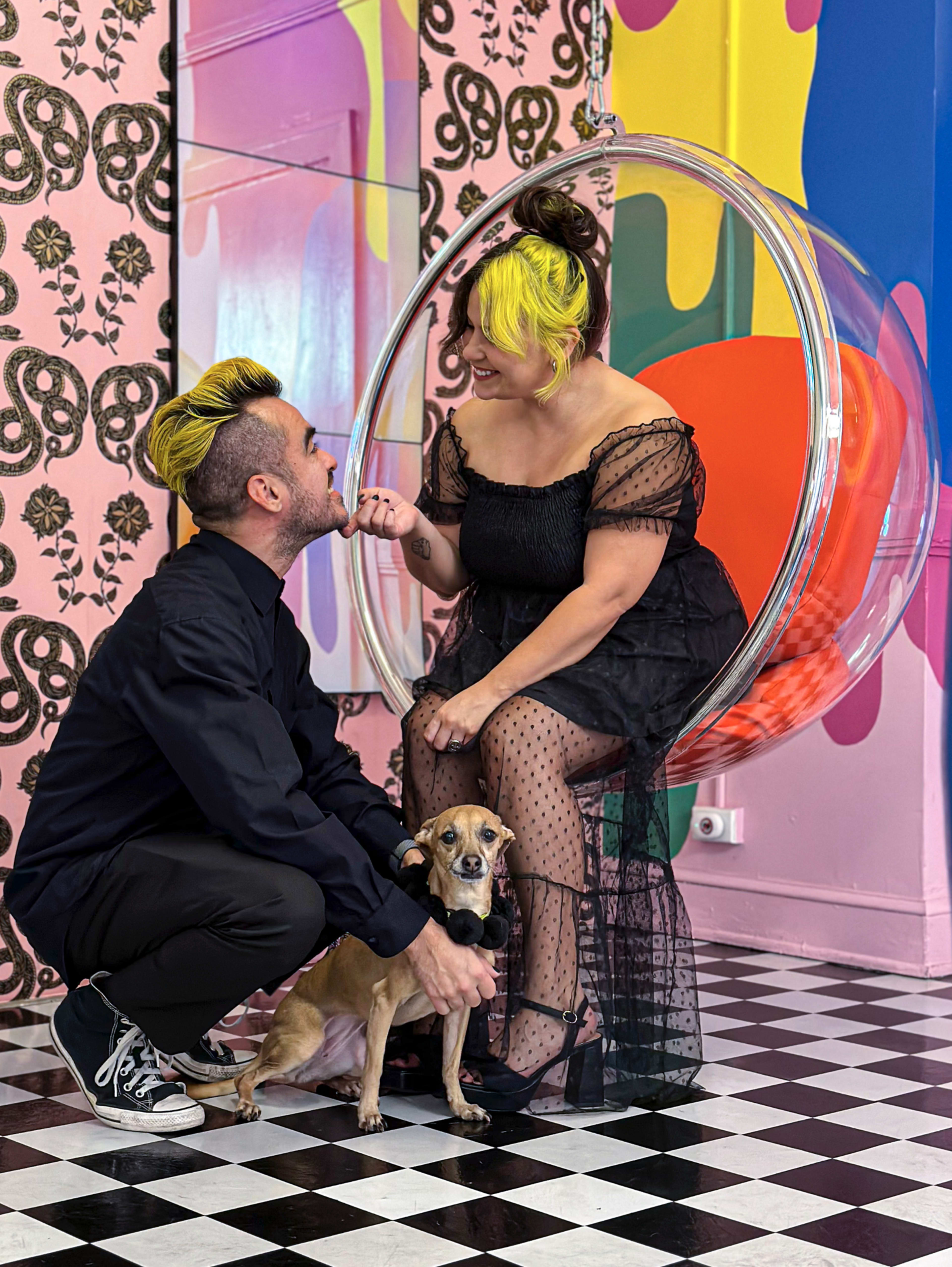 A couple sitting with their dog in an eclectic space during a photo shoot.