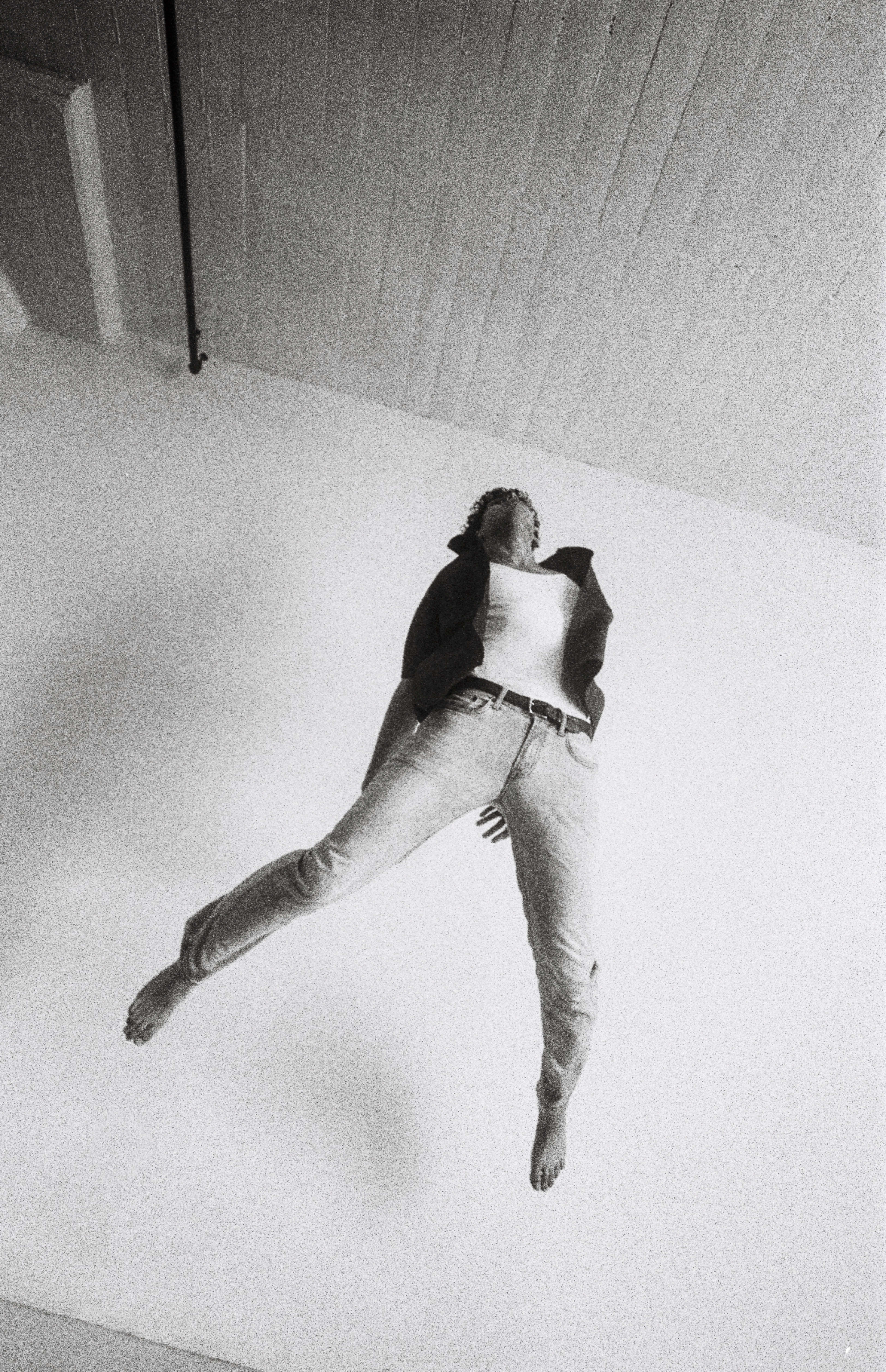 A man is jumping in the air in a black and white photo shoot.