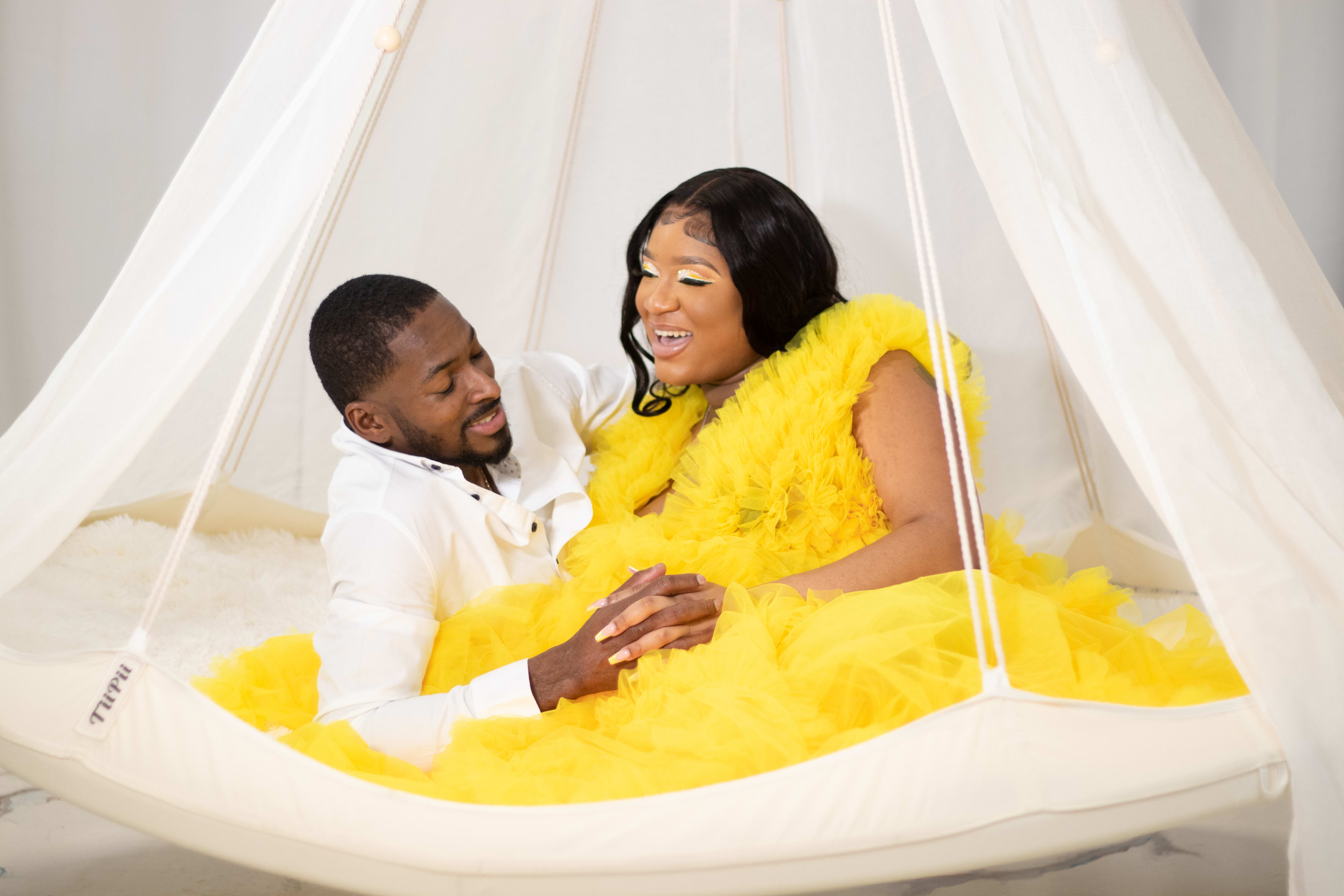 Un homme et une femme dans une robe jaune posant pour un shooting photo.