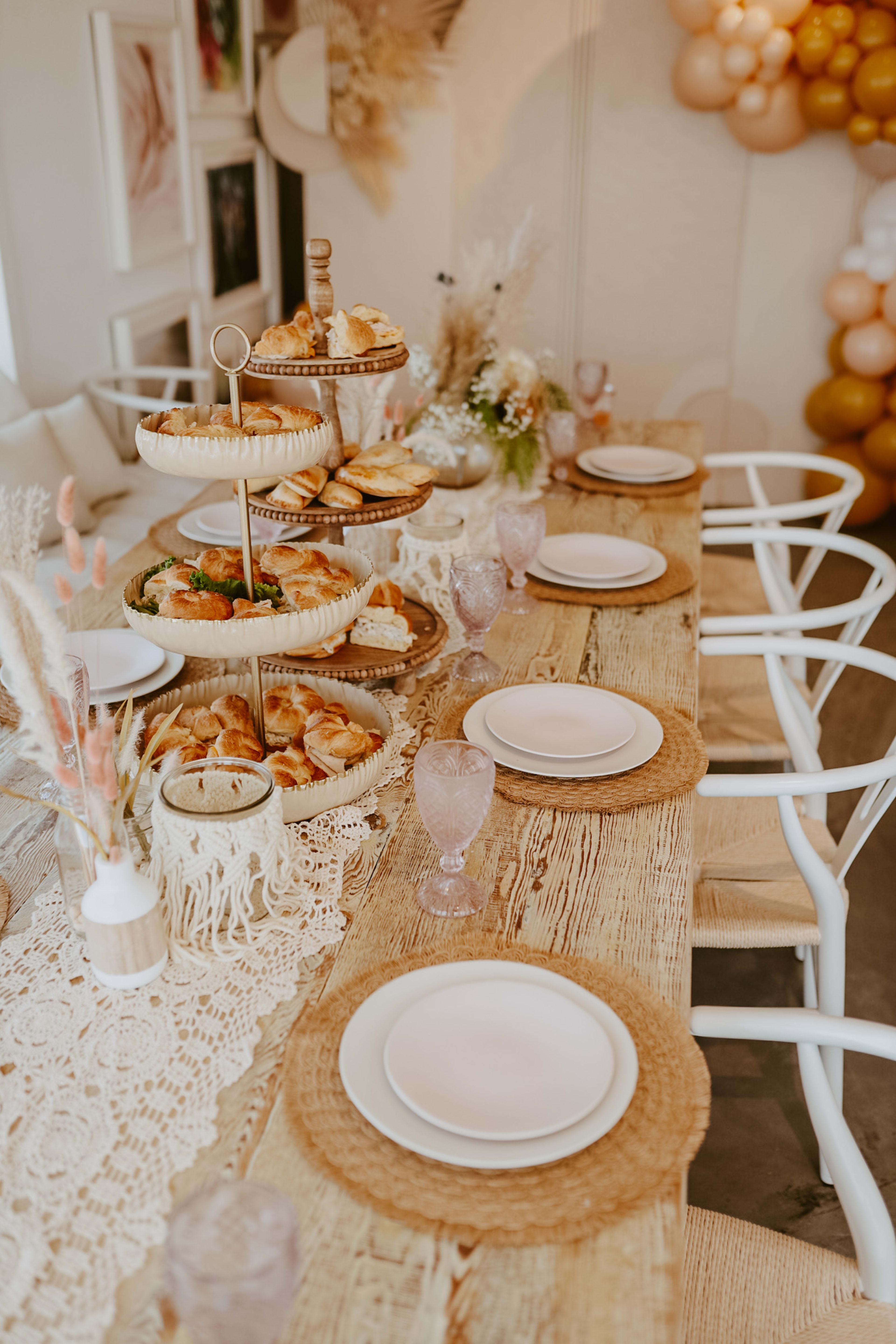 Une table avec des pâtisseries et des assiettes blanches pour un brunch de baby shower.