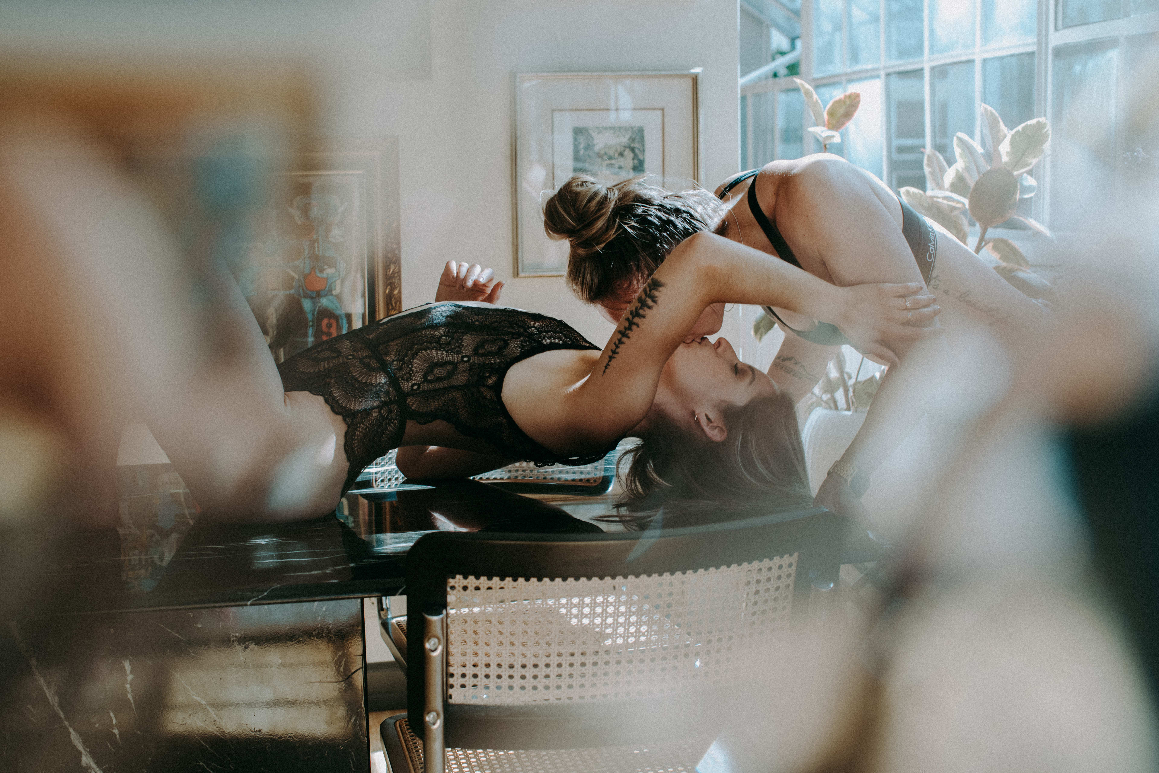 A photoshoot featuring a couple of women laying on top of a table wearing lingerie.