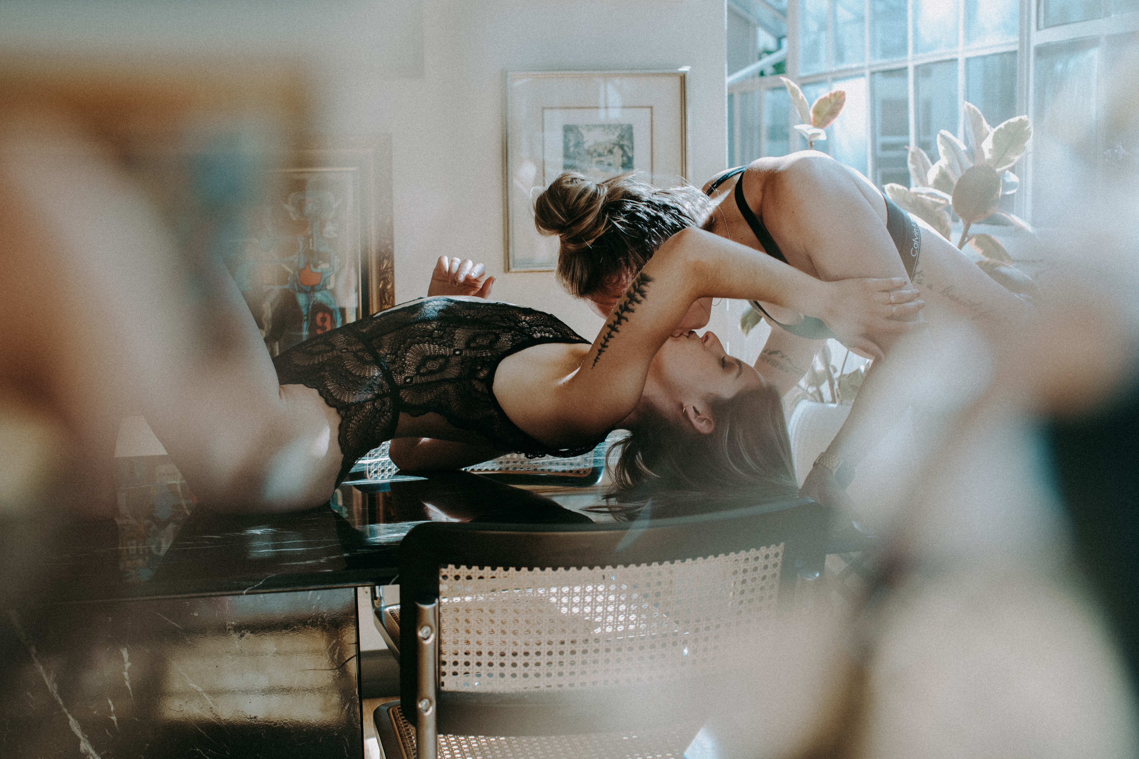 A photo shoot featuring a couple of women lying on top of a table wearing lingerie.