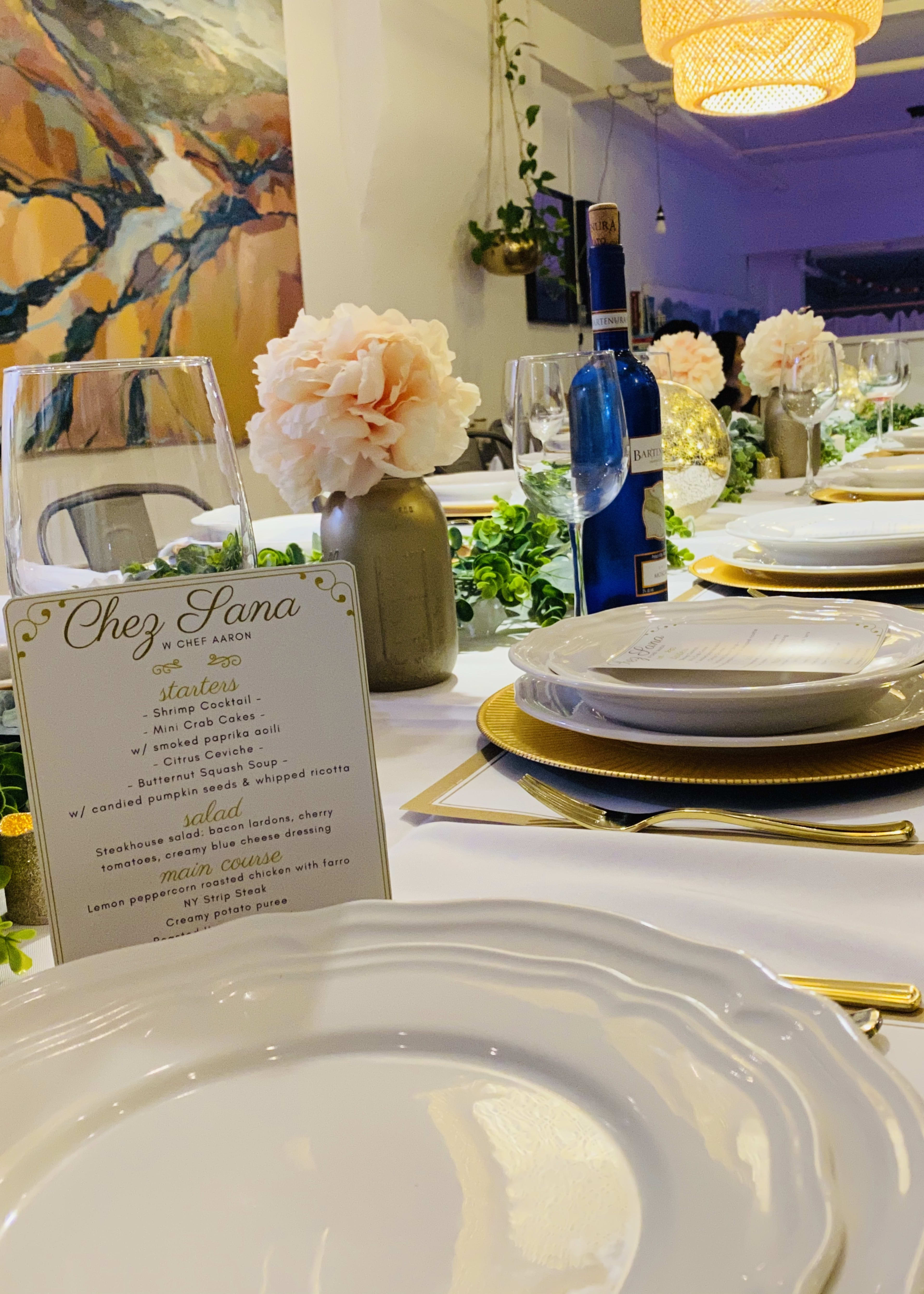 Una mesa dorada y blanca puesta con un menú para celebrar una cena formal.