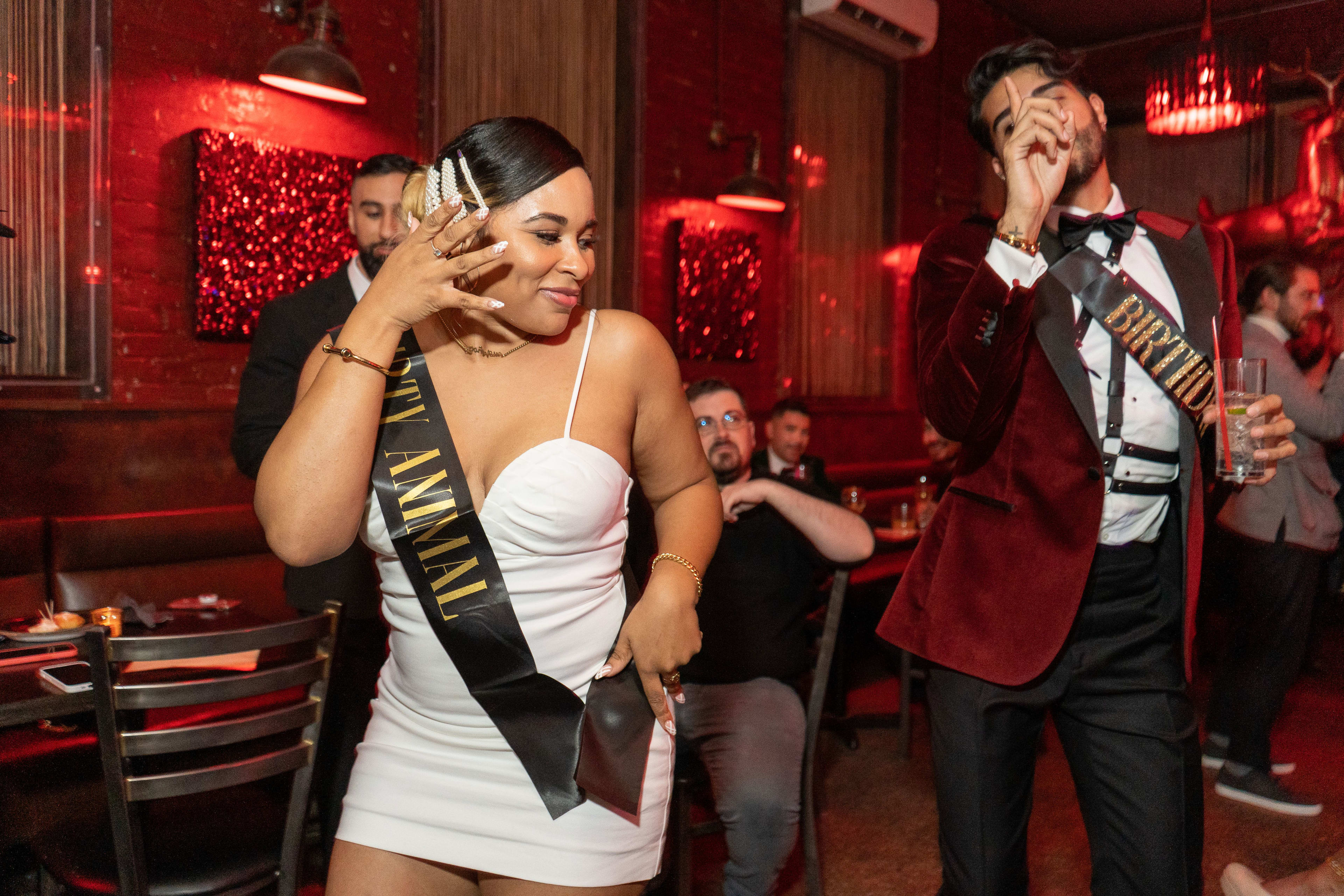 A woman in a white dress standing next to a man in a red suit at a party.