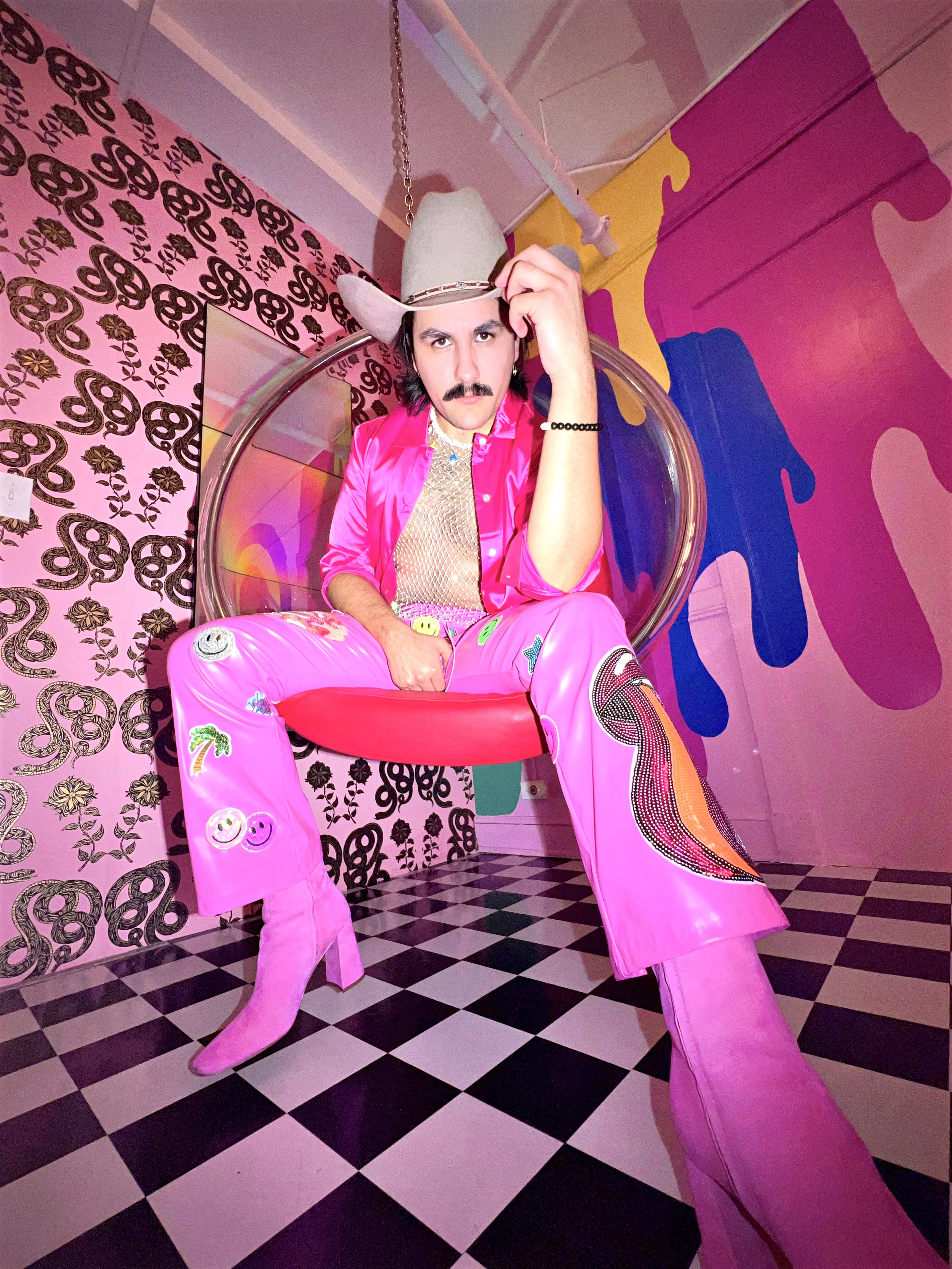 A cowboy sitting in a chair with a pink outfit and a hat on.
