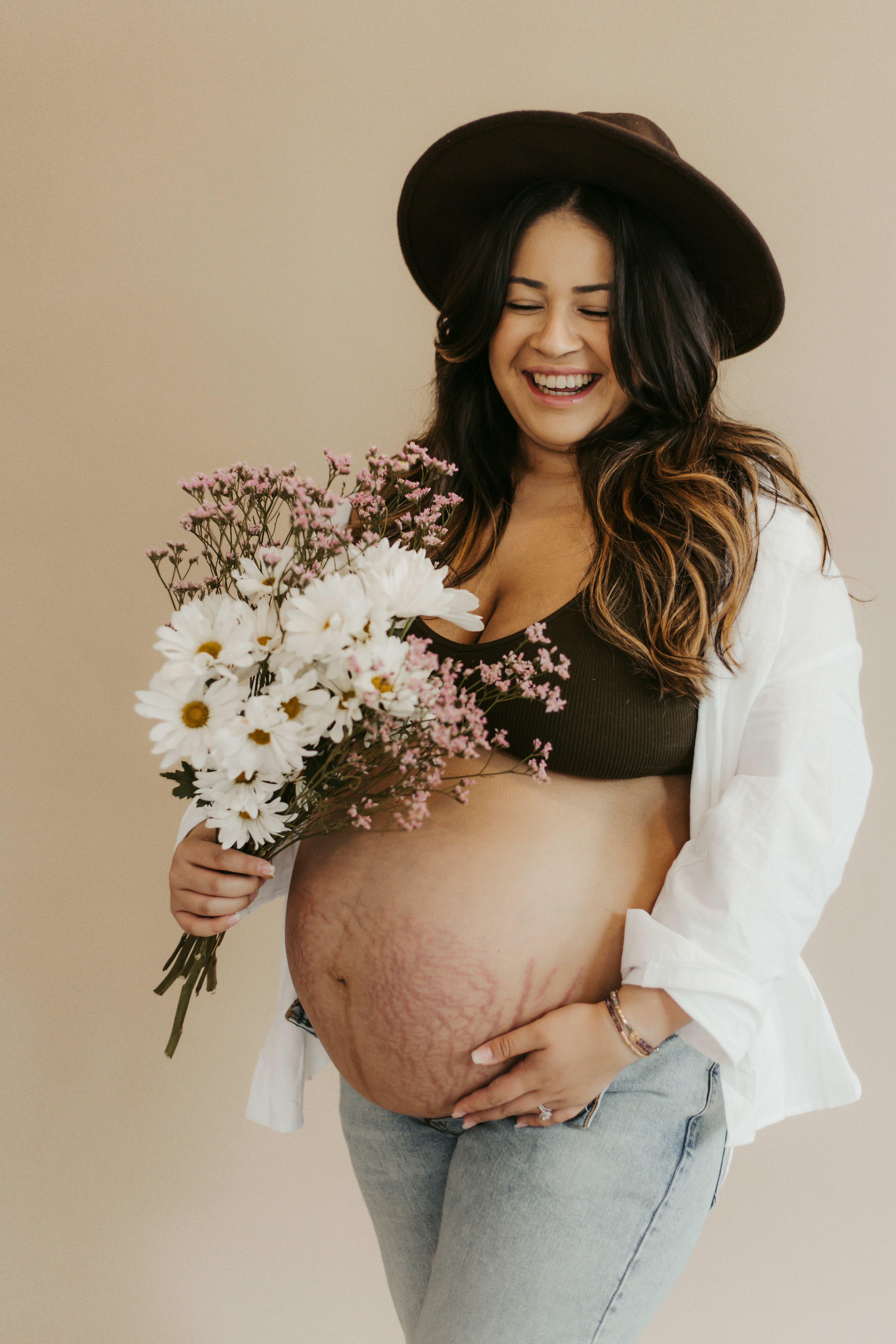A country-themed maternity photo shoot featuring a pregnant woman holding a bouquet of flowers.