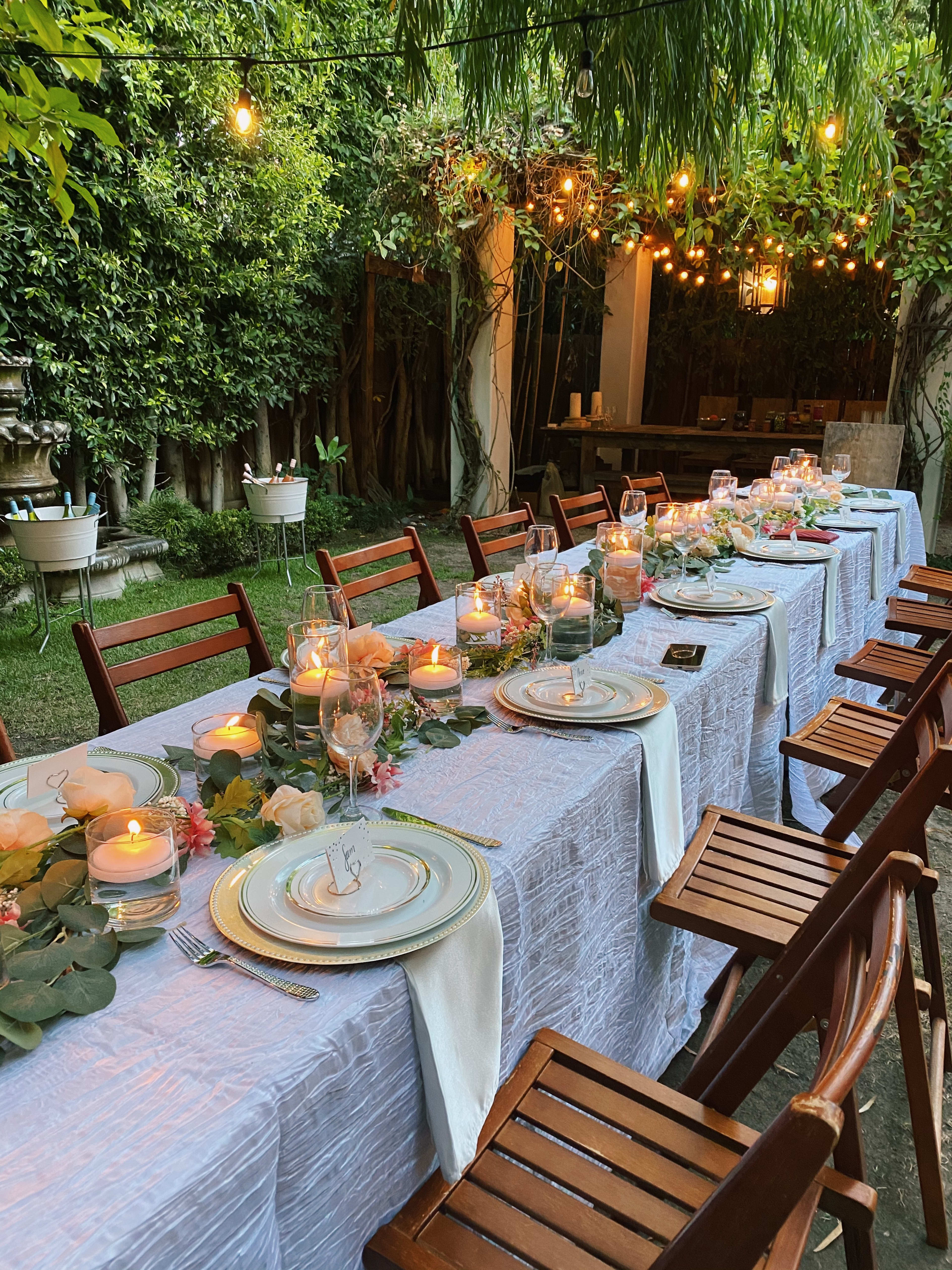 Una mesa de jardín con velas y platos sobre ella.