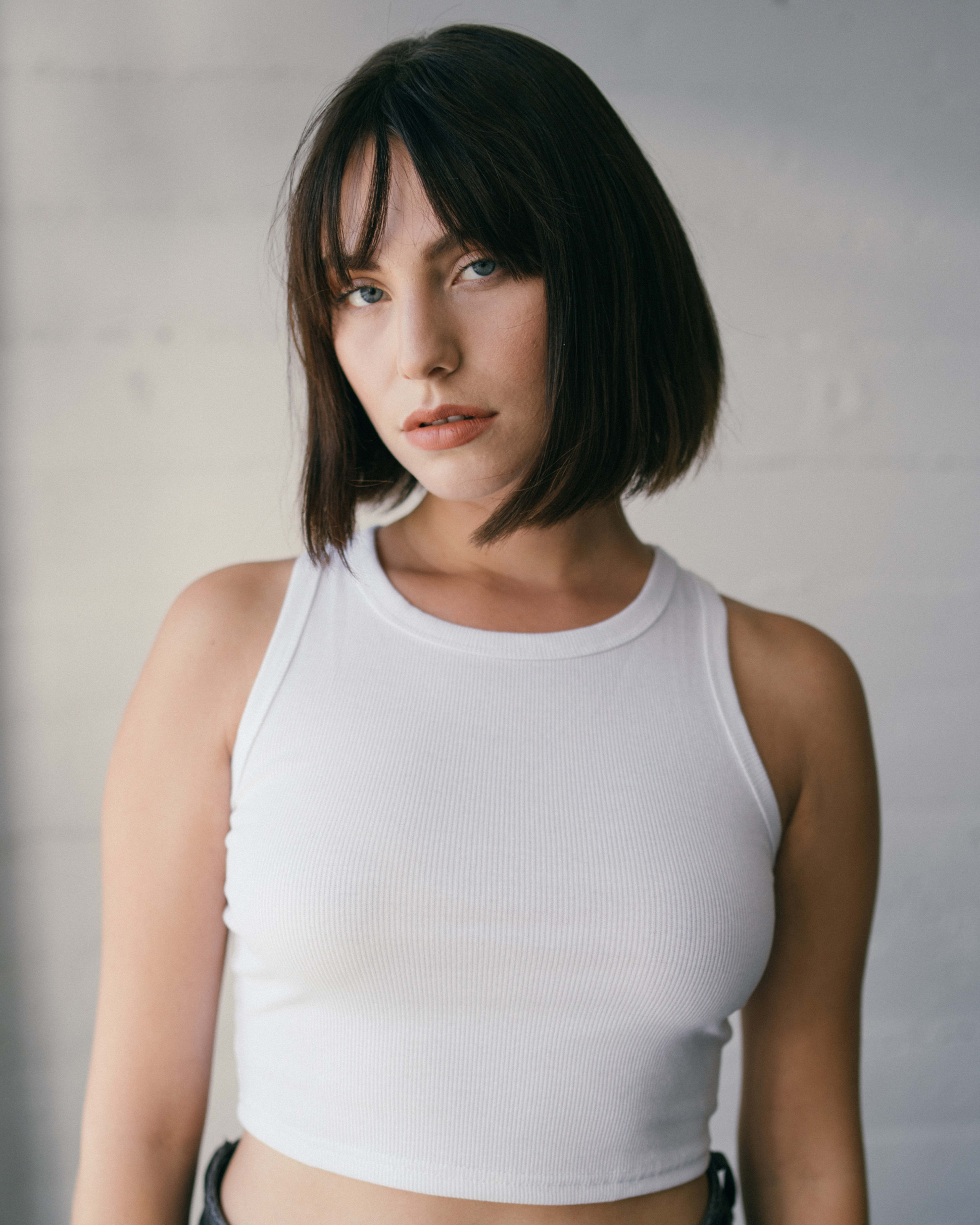 A woman in a white crop top posing for a minimalist  headshot.