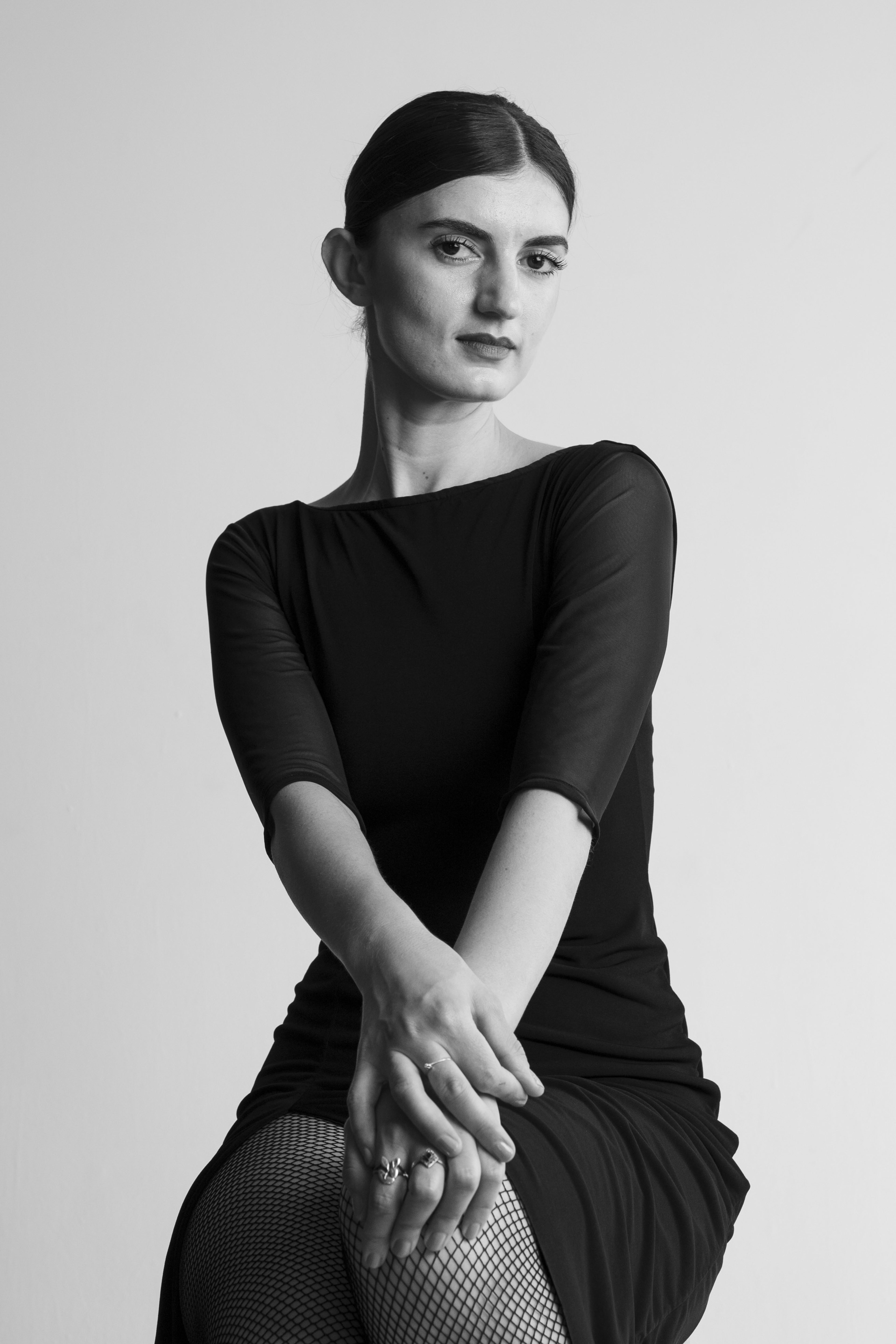 A black and white portrait of a woman in fishnet stockings.