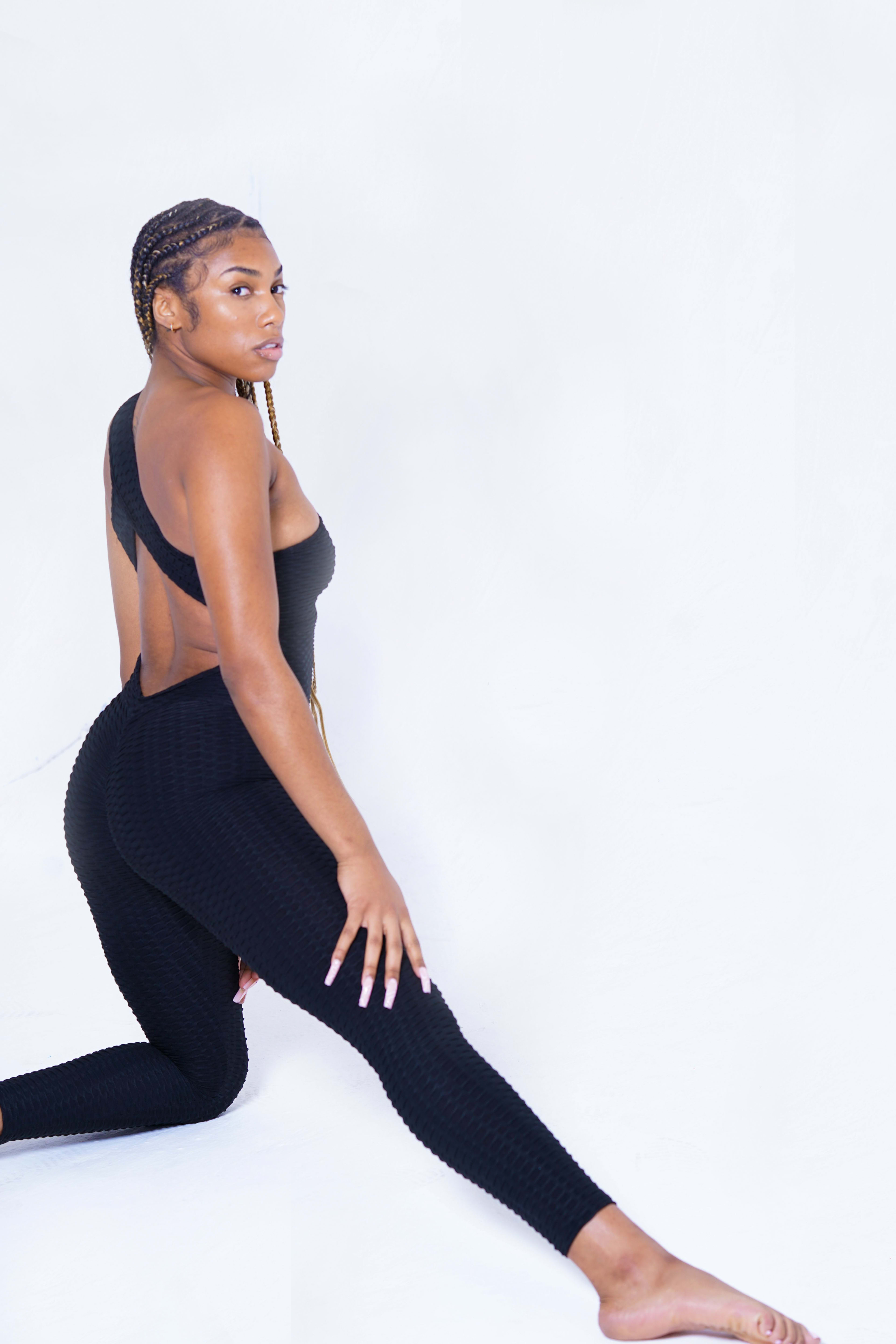 Une femme en brassière noire et leggings pour un shooting photo fitness.