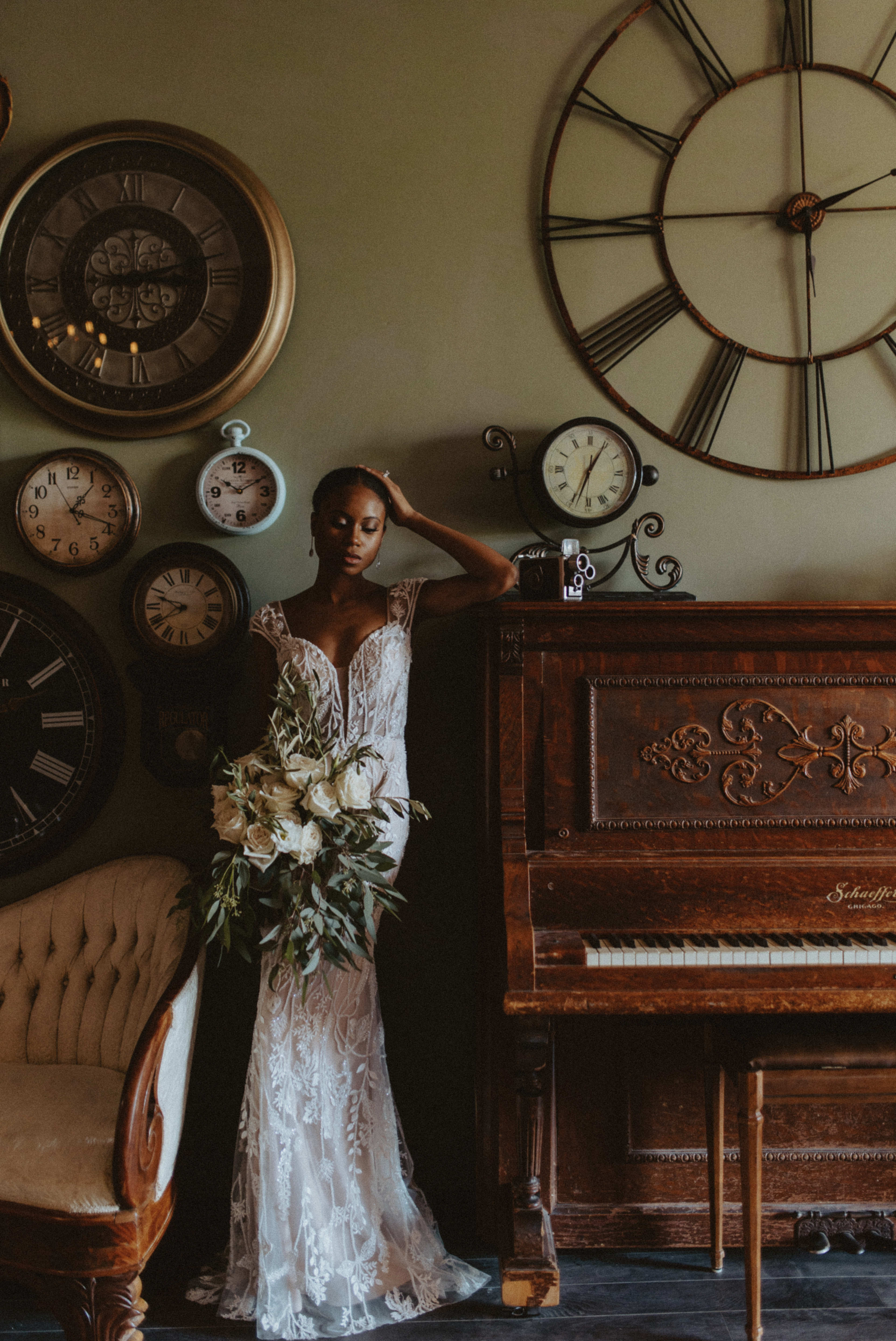 A rustic photo shoot featuring a woman in a wedding dress posing next to a piano surrounded by clocks.