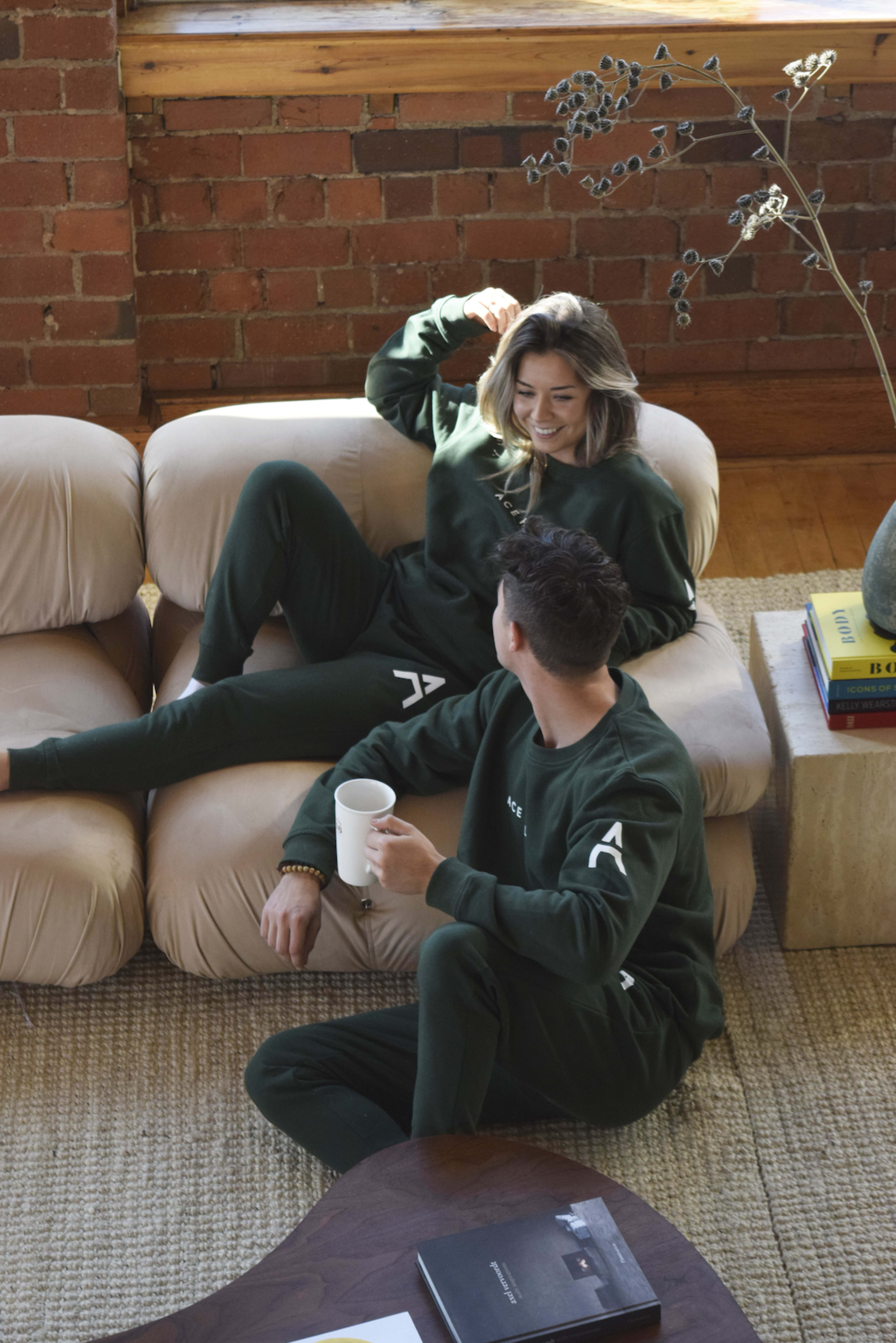 Un couple vêtu de vert assis sur un canapé rustique pour un shooting photo.