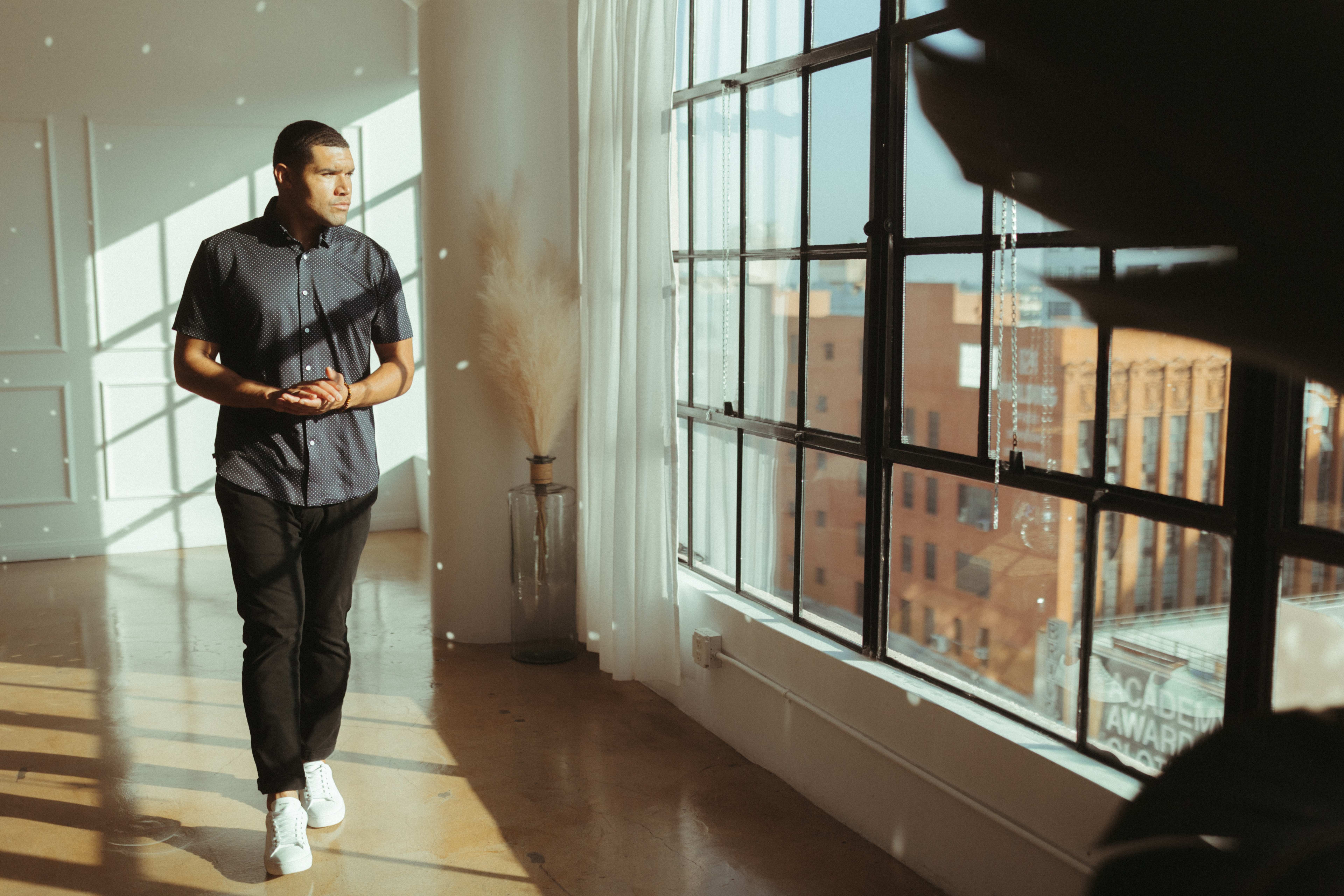 A man posing for a photoshoot in front of a large window.