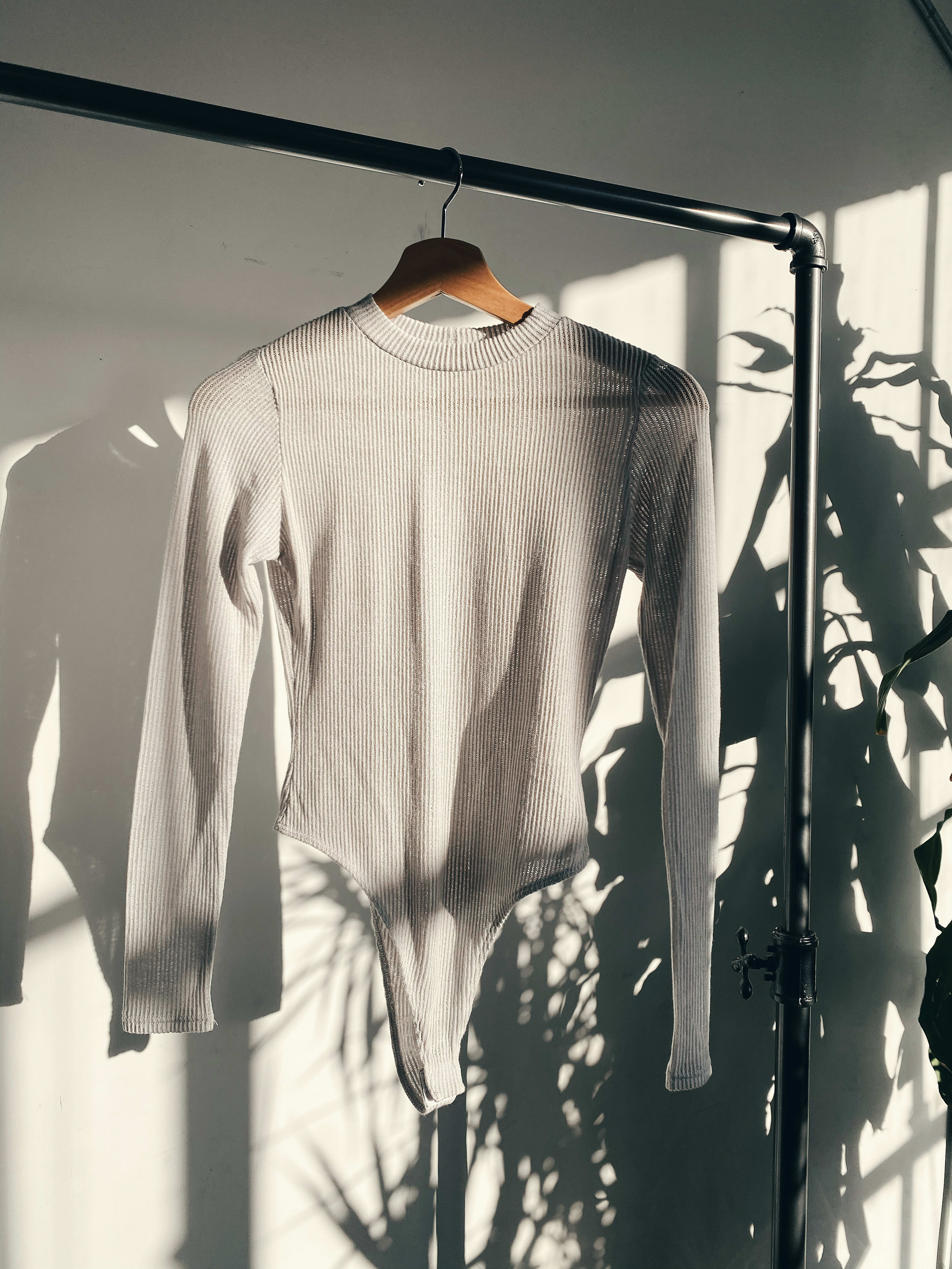 A white boho sweater on a clothes rack for a product shoot.