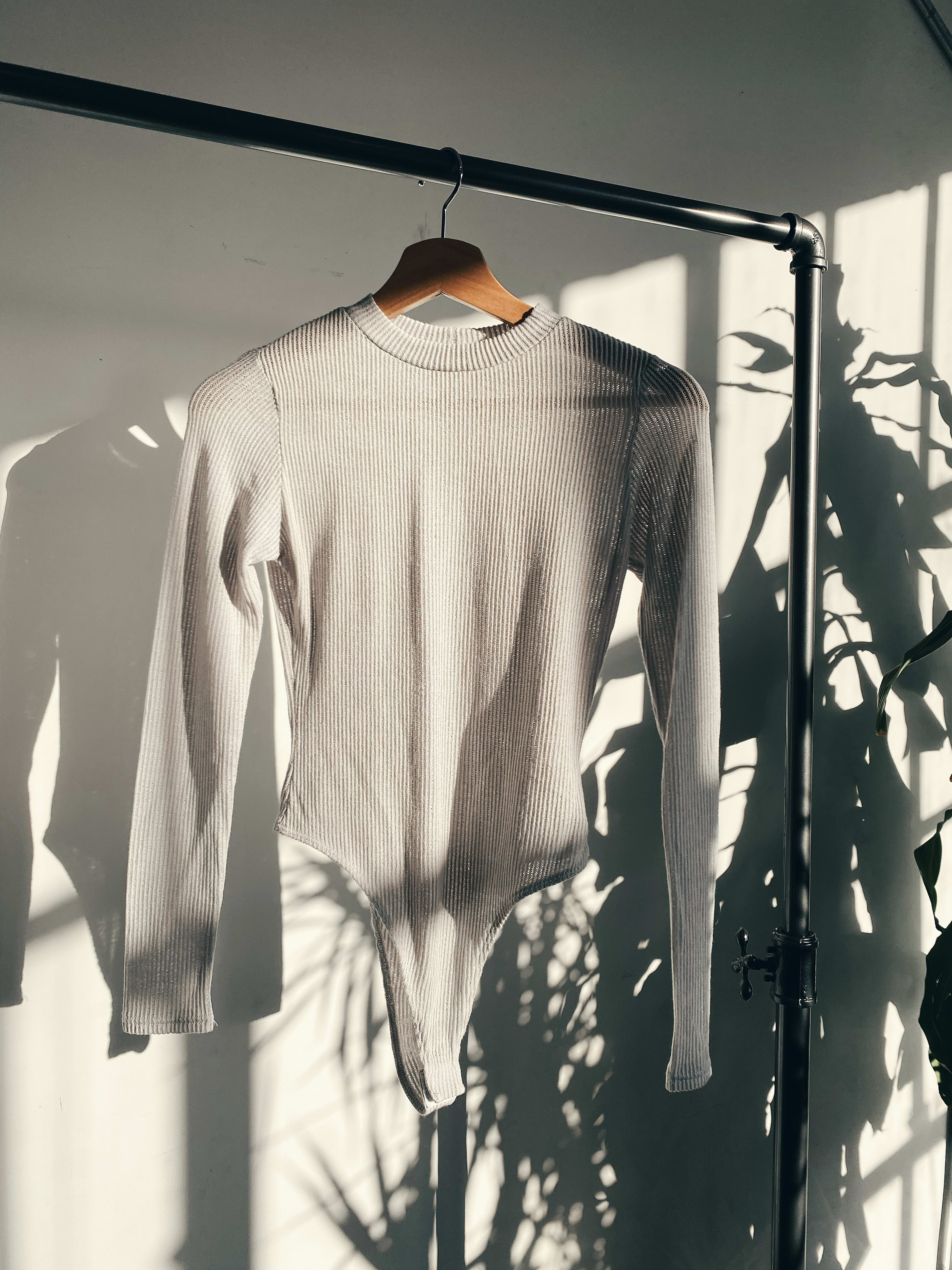 Un pull de style boho blanc sur un porte-vêtements pour un shooting photo de produit.